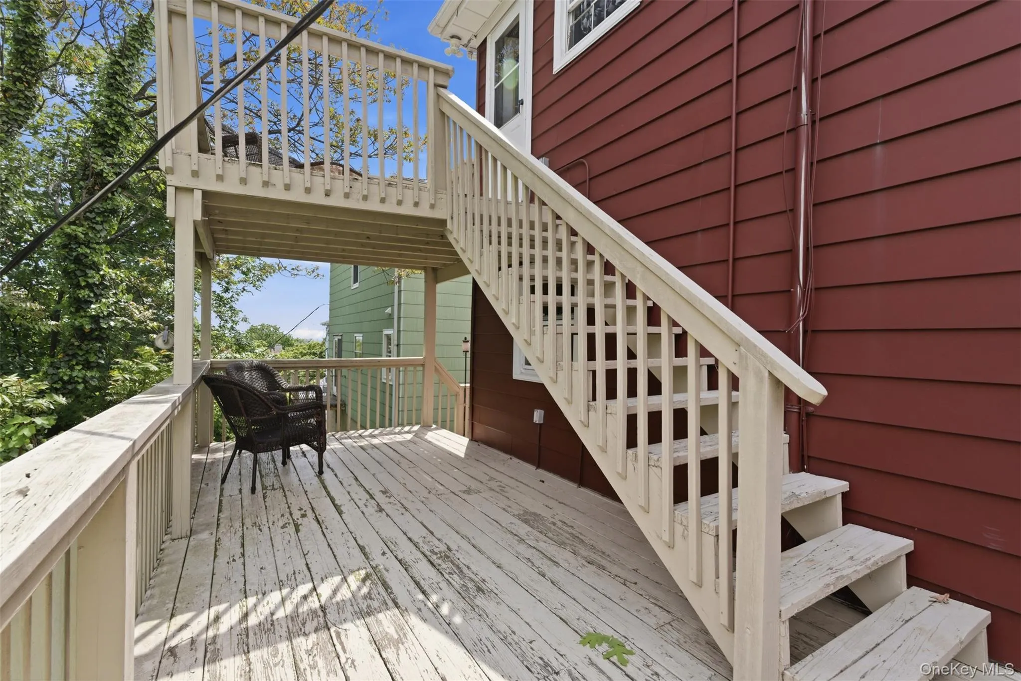 Multi-level outdoor deck featuring a lower level with a privacy rail and an upper-level balcony, complemented by exterior siding in a rich red hue Multi-level outdoor deck featuring a lower level with a privacy rail and an upper-level balcony, complemented by exterior siding in a rich red hue