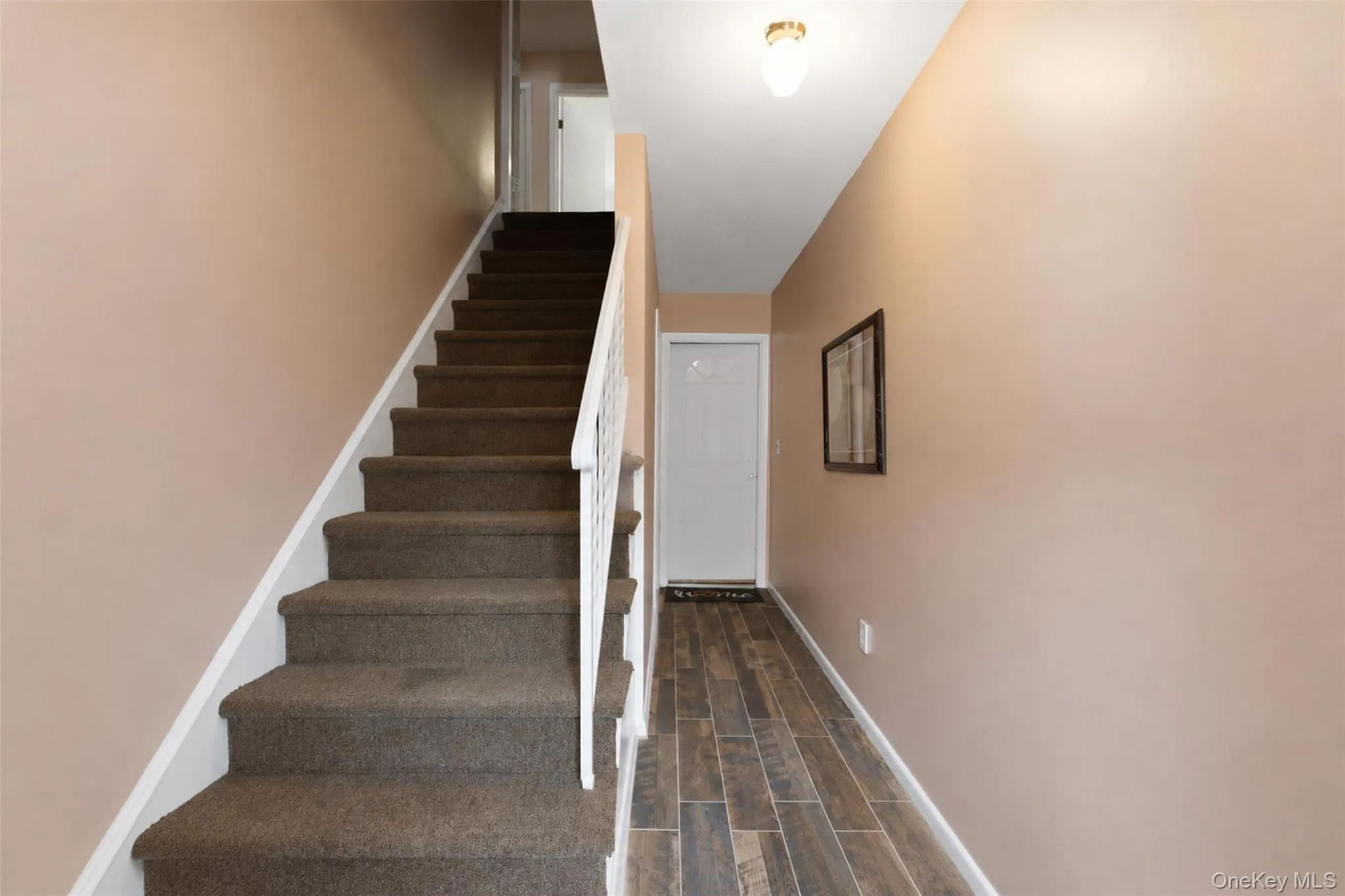 Inviting entryway with wood-finish flooring extending from the white front door Inviting entryway with wood-finish flooring extending from the white front door
