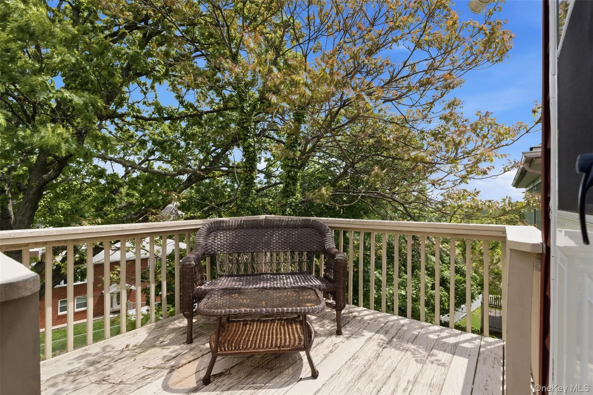 Outdoor deck featuring wooden flooring, white painted railings, and mature tree canopy Outdoor deck featuring wooden flooring, white painted railings, and mature tree canopy