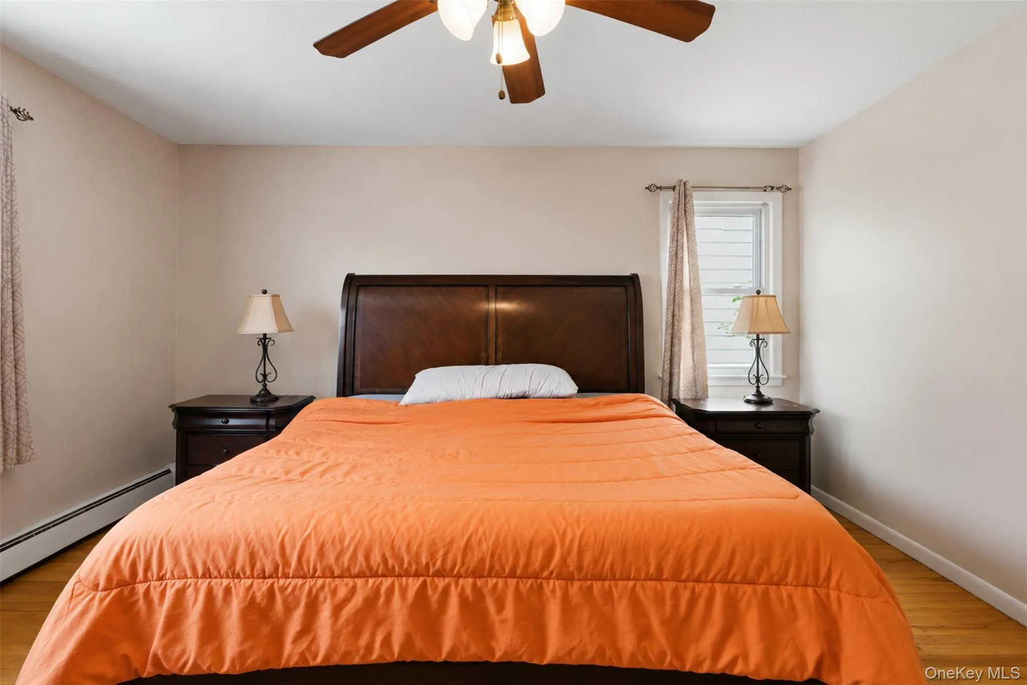 Spacious room featuring wood-finish flooring, a built-in ceiling fan with integrated lighting, and neutral wall tones Spacious room featuring wood-finish flooring, a built-in ceiling fan with integrated lighting, and neutral wall tones