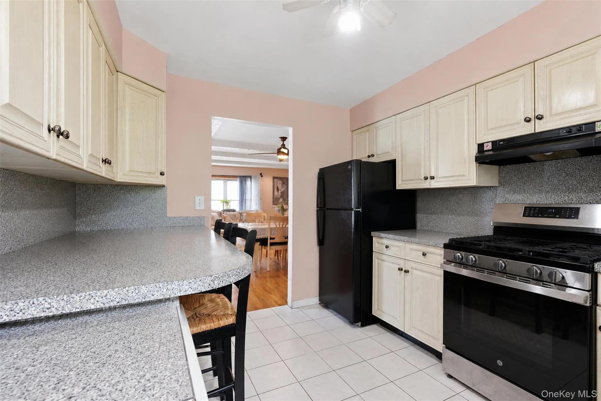 Kitchen featuring light-toned cabinetry, speckled countertops, and a white tiled floor Kitchen featuring light-toned cabinetry, speckled countertops, and a white tiled floor