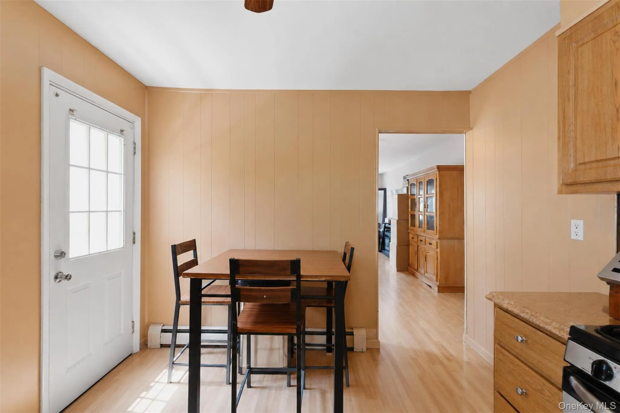 Kitchen area featuring wood-finish flooring, a white paneled door with divided light, and wall paneling Kitchen area featuring wood-finish flooring, a white paneled door with divided light, and wall paneling