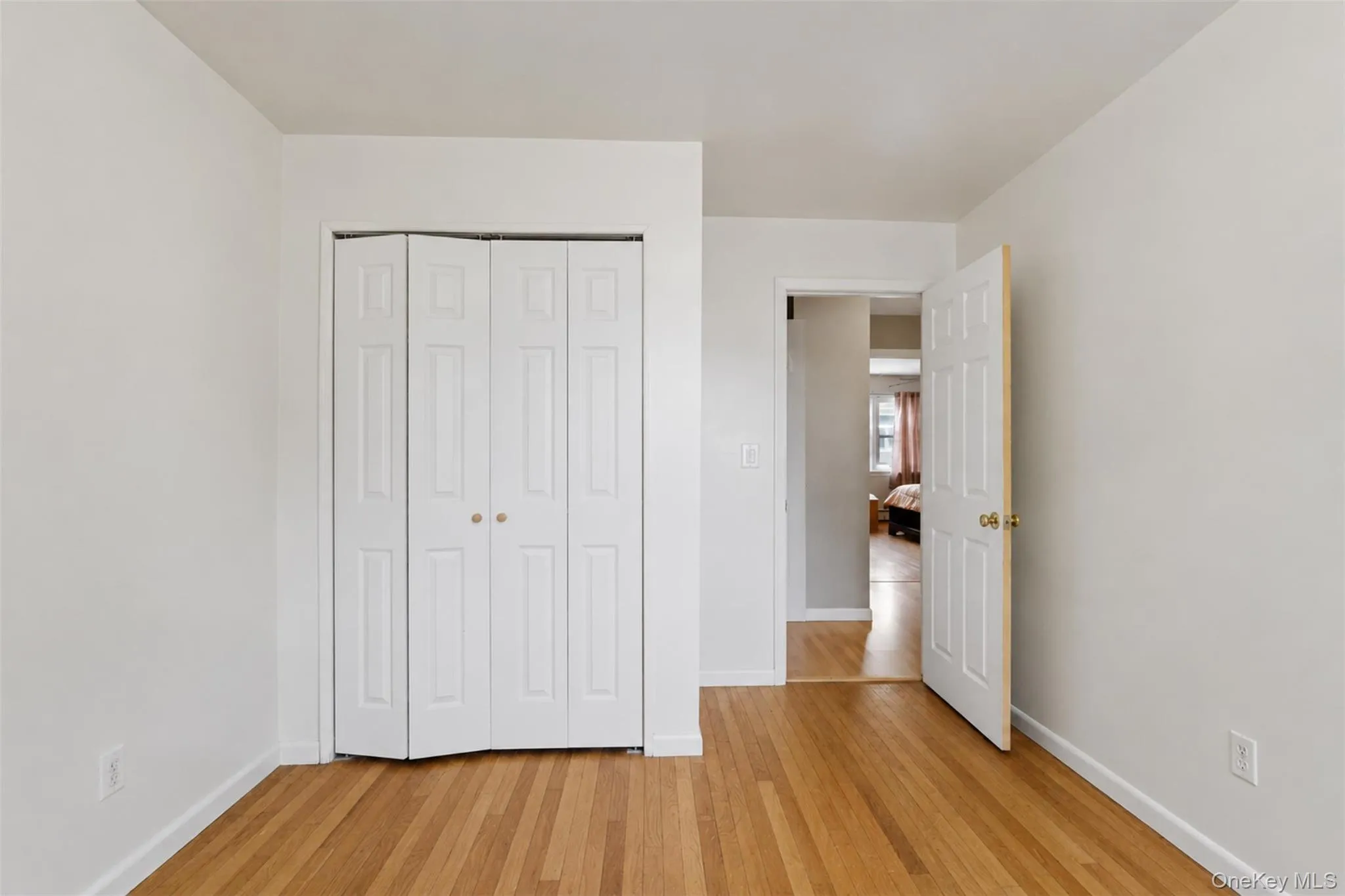 Light wood-finish flooring with white baseboards, white walls, and a white ceiling Light wood-finish flooring with white baseboards, white walls, and a white ceiling