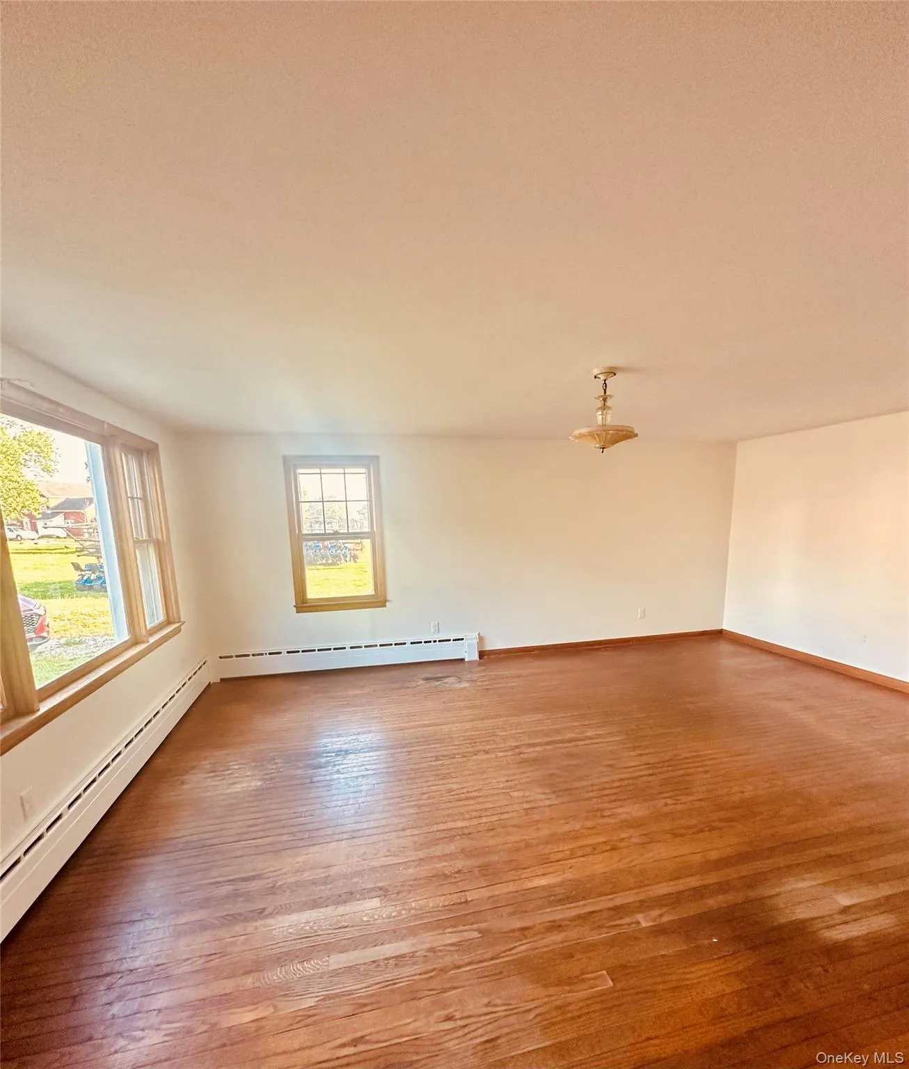 Spacious room featuring hardwood flooring and multiple windows Spacious room featuring hardwood flooring and multiple windows