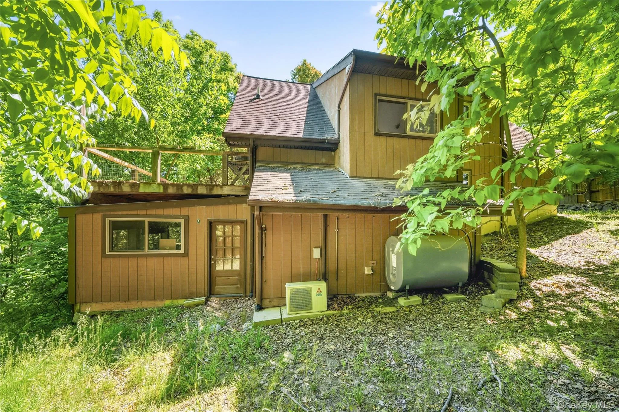Multi-level exterior featuring wood siding, a brown shingle roof, a glass-paneled entry door, and an upper-level wood deck with railing Multi-level exterior featuring wood siding, a brown shingle roof, a glass-paneled entry door, and an upper-level wood deck with railing
