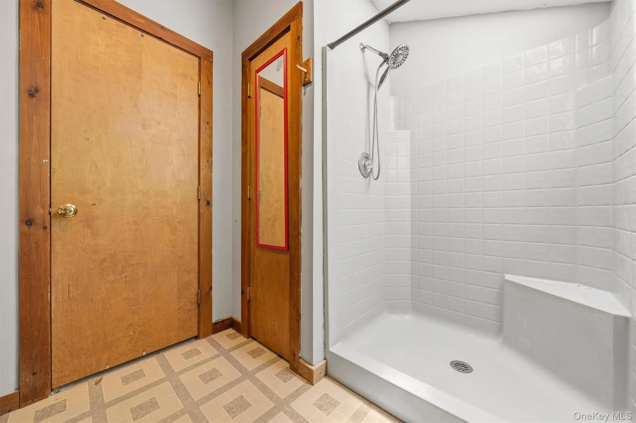 Shower stall featuring white subway tile, an integrated corner seat, a multi-function shower head, and a clear glass enclosure Shower stall featuring white subway tile, an integrated corner seat, a multi-function shower head, and a clear glass enclosure