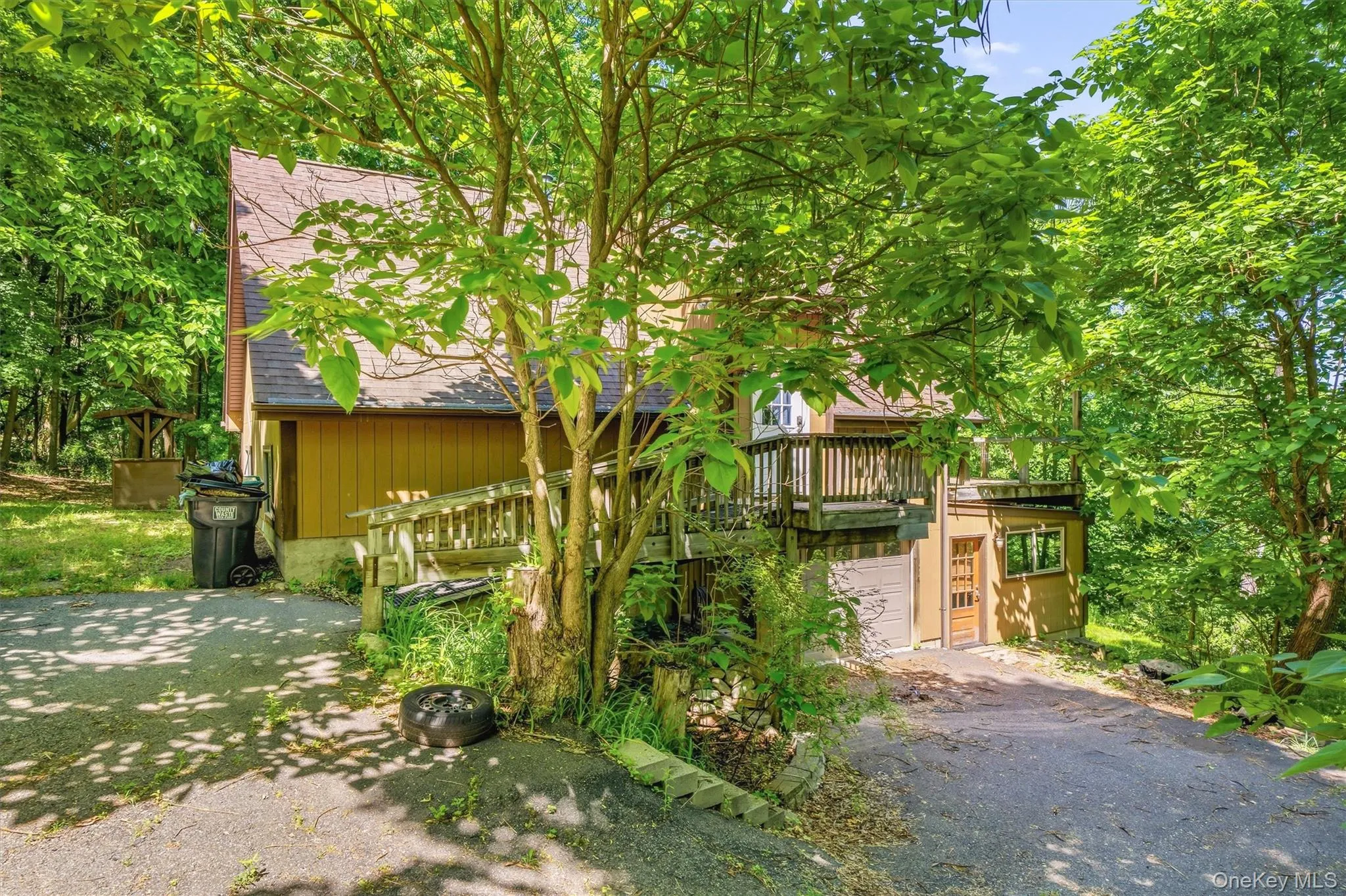 Wooded property featuring a multi-level dwelling with a gabled roof Wooded property featuring a multi-level dwelling with a gabled roof