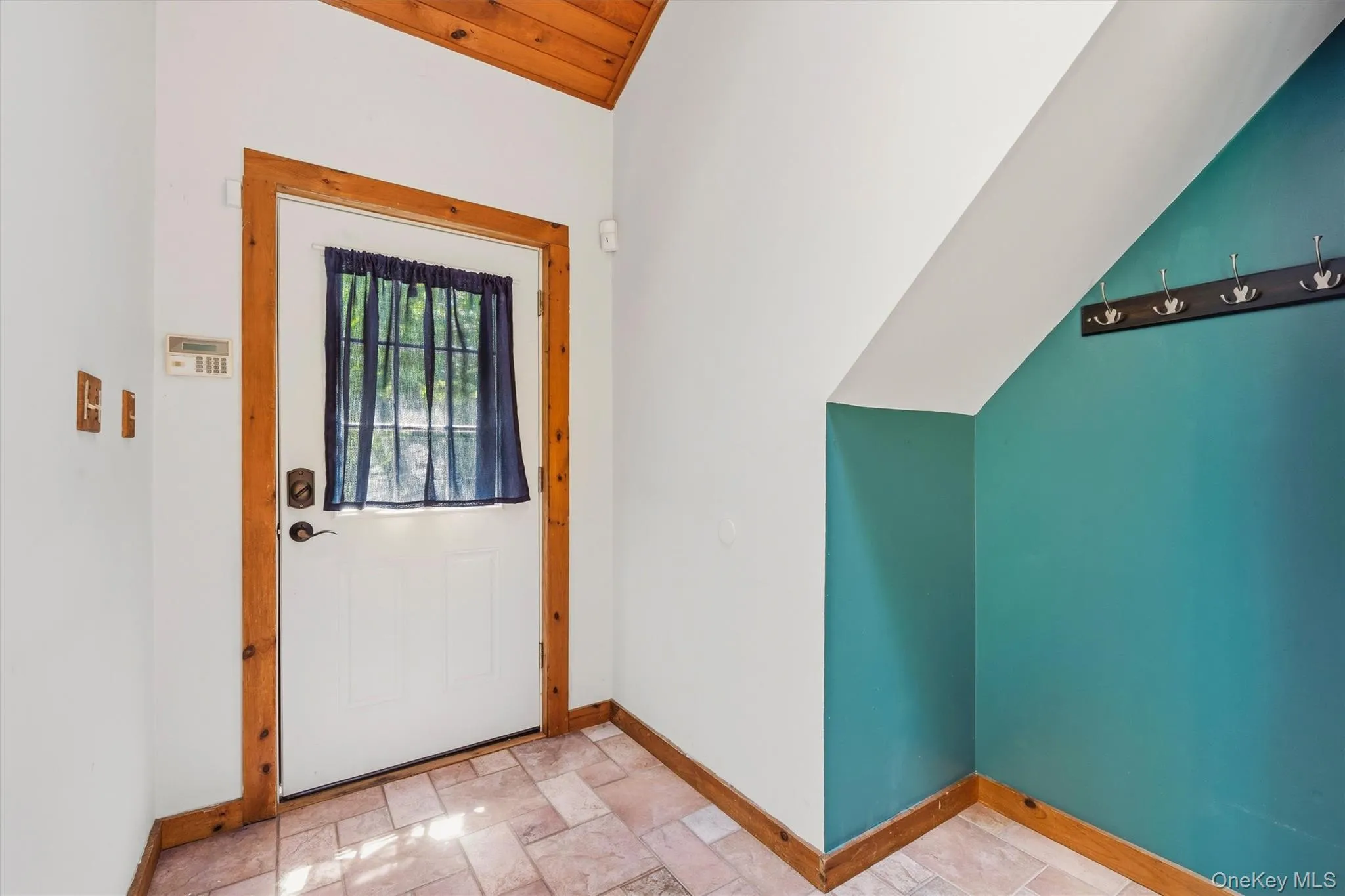 Entryway featuring a white door with a window, wood trim, and tile flooring Entryway featuring a white door with a window, wood trim, and tile flooring