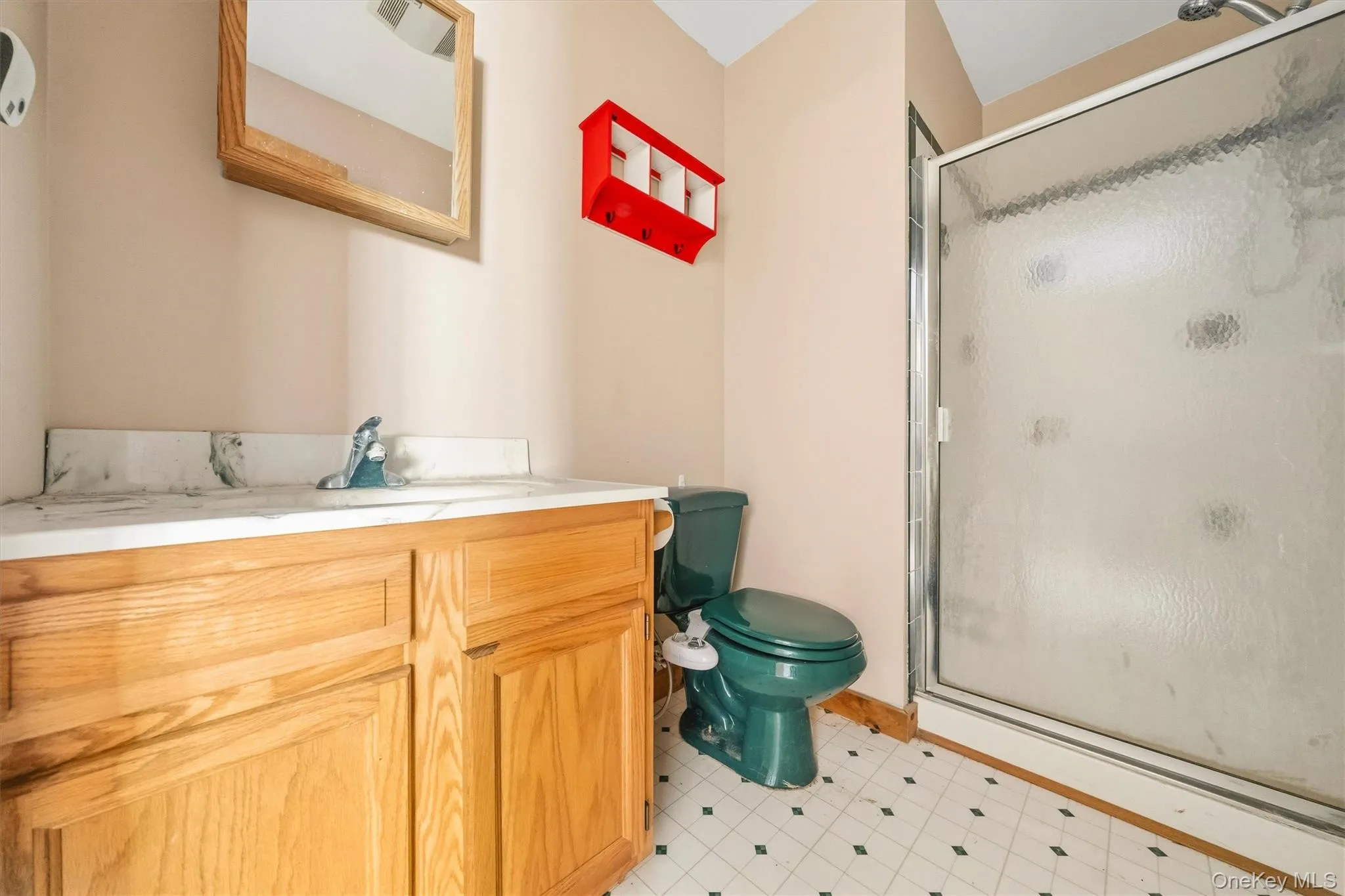 Bathroom featuring a vanity with wood-finish cabinetry, a white countertop, and a framed mirror Bathroom featuring a vanity with wood-finish cabinetry, a white countertop, and a framed mirror
