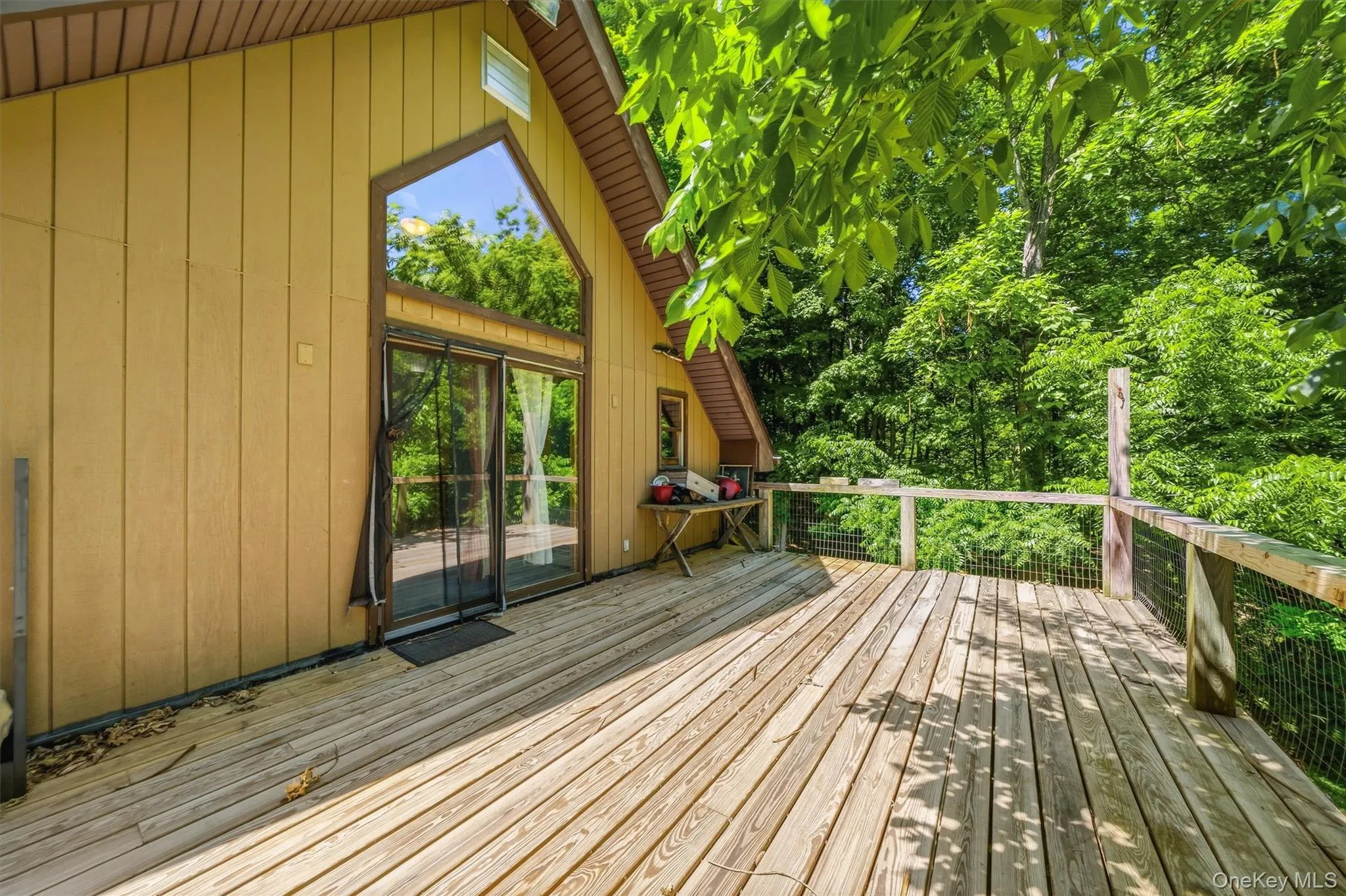 Expansive wood deck with a natural wood railing, surrounded by mature trees Expansive wood deck with a natural wood railing, surrounded by mature trees