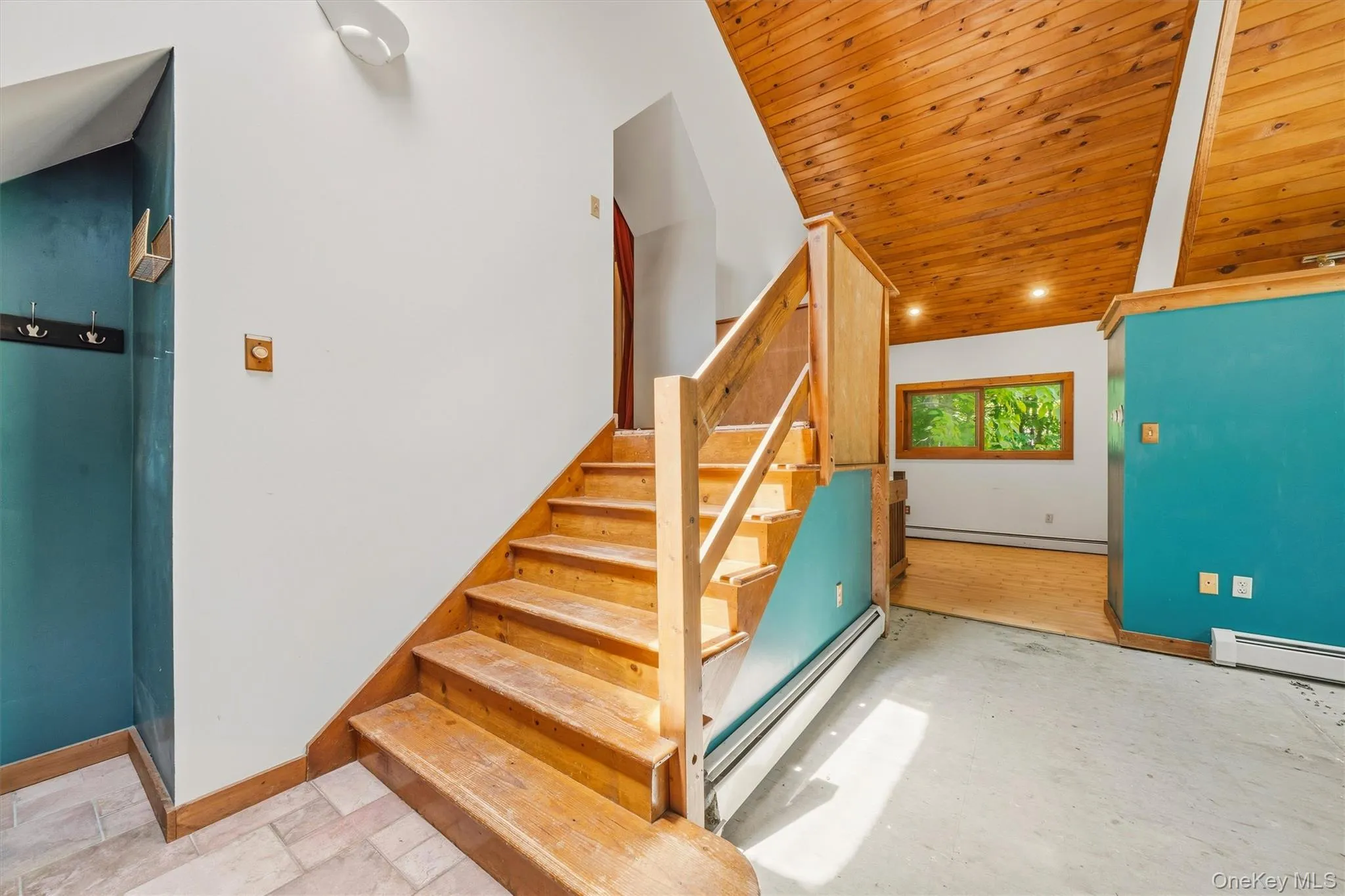 Wood-finish staircase with natural wood railing, vaulted wood-paneled ceiling, and wall-mounted lighting Wood-finish staircase with natural wood railing, vaulted wood-paneled ceiling, and wall-mounted lighting