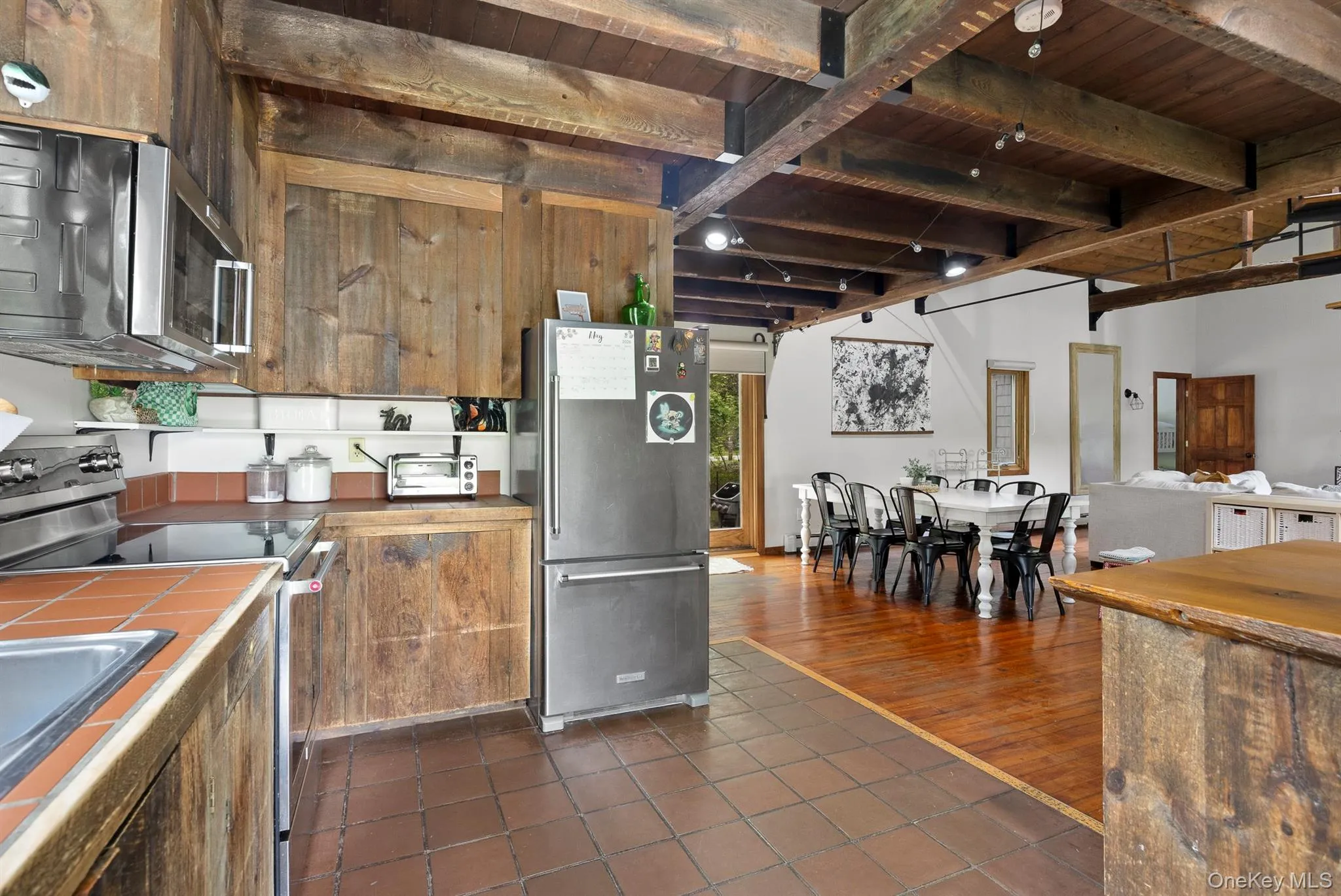 Kitchen featuring wood cabinetry, stainless steel appliances, and terra cotta tile flooring Kitchen featuring wood cabinetry, stainless steel appliances, and terra cotta tile flooring