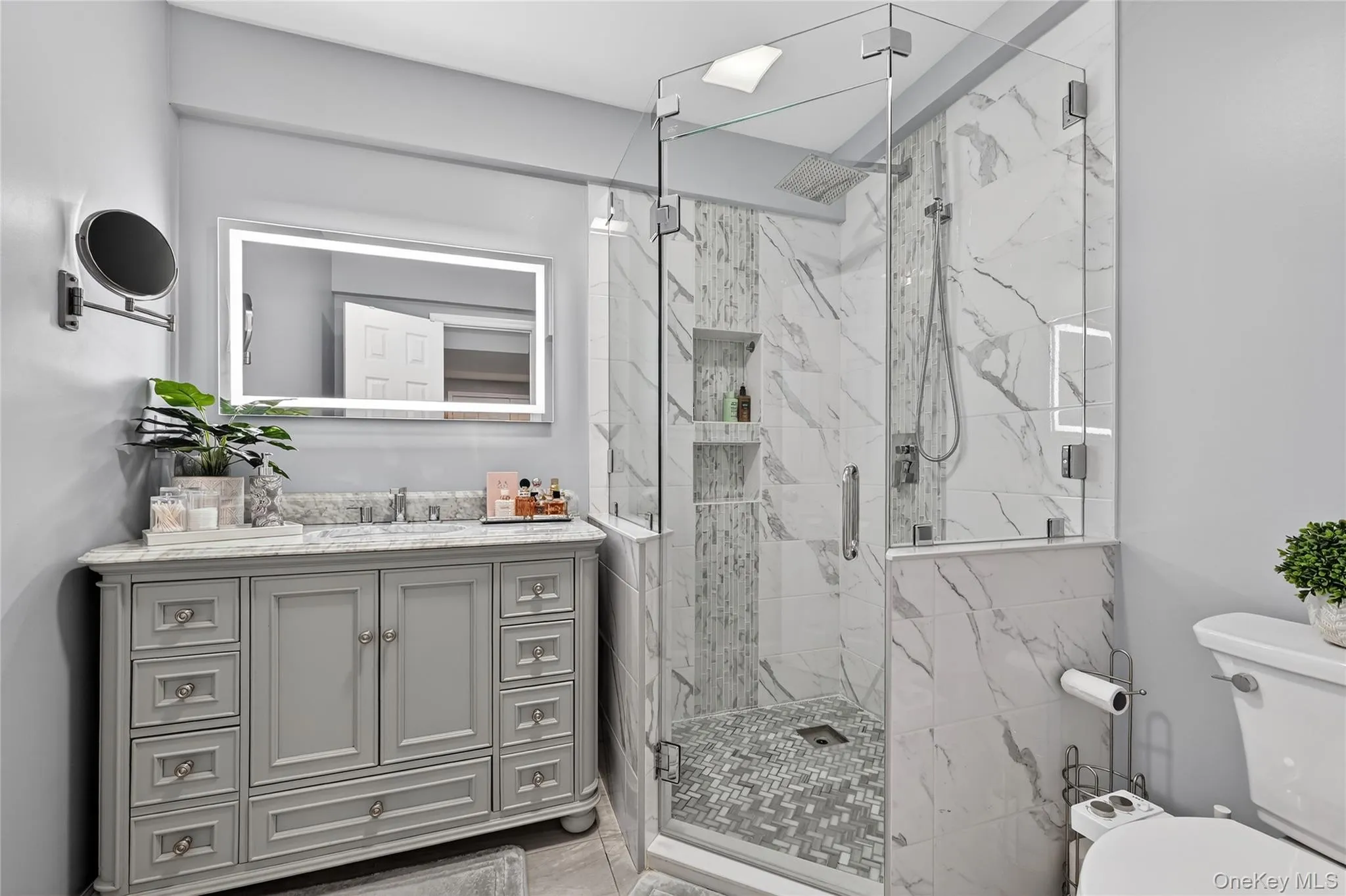 Contemporary bathroom featuring a spacious glass-enclosed shower, integrated shower niche shelving, and a vanity with a stone countertop Contemporary bathroom featuring a spacious glass-enclosed shower, integrated shower niche shelving, and a vanity with a stone countertop