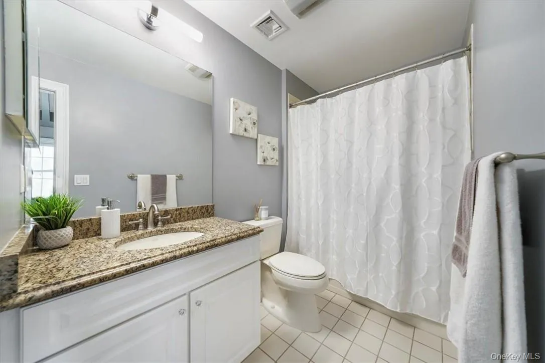Bathroom featuring tile floors, vanity with extensive cabinet space, and toilet Bathroom featuring tile floors, vanity with extensive cabinet space, and toilet