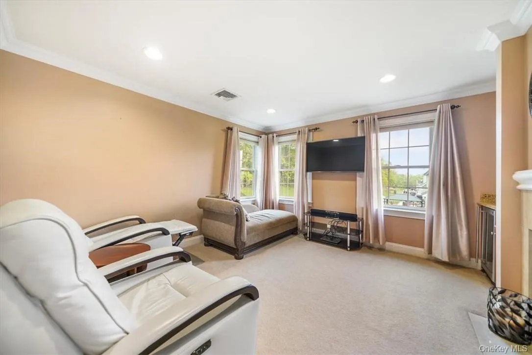 Sitting area in Master bedroom featuring light carpet and crown molding and fireplace Sitting area in Master bedroom featuring light carpet and crown molding and fireplace