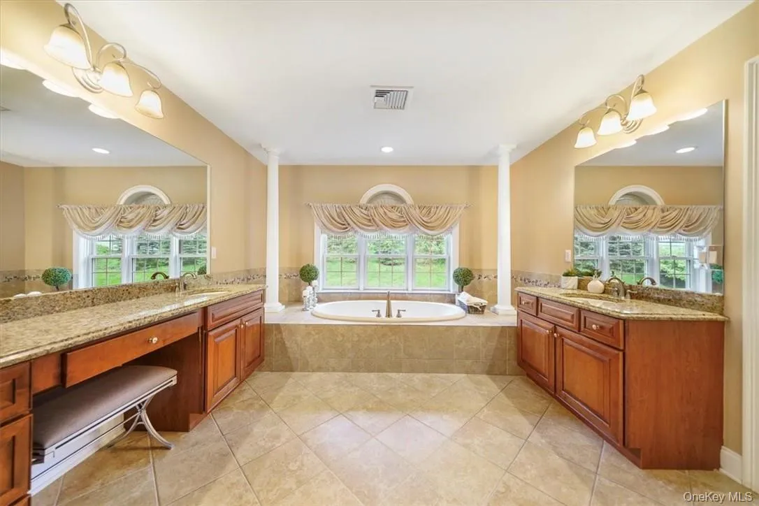 Bathroom featuring tile floors, a relaxing tiled bath, decorative columns, and double vanity Bathroom featuring tile floors, a relaxing tiled bath, decorative columns, and double vanity