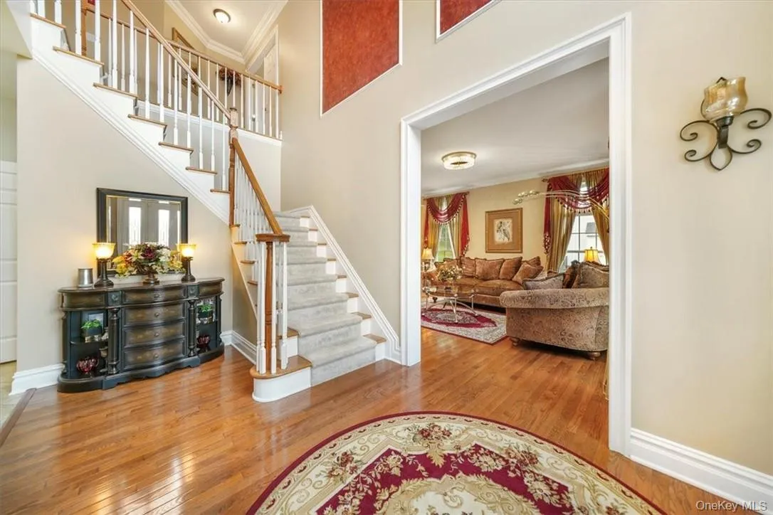 Stairway with a towering ceiling, hardwood / wood-style flooring, and crown molding Stairway with a towering ceiling, hardwood / wood-style flooring, and crown molding
