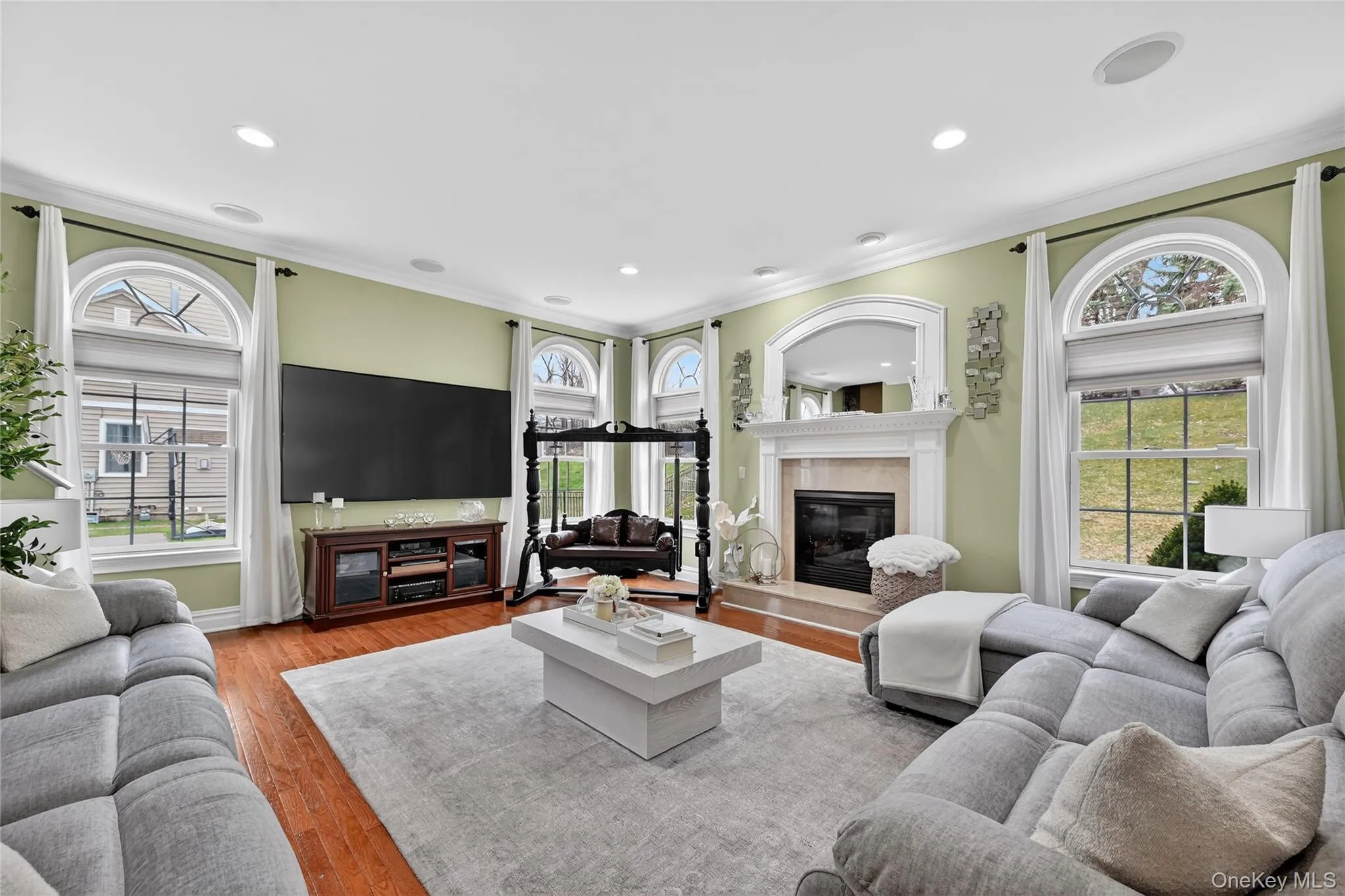 Living area featuring wood-finish flooring and multiple arched windows Living area featuring wood-finish flooring and multiple arched windows