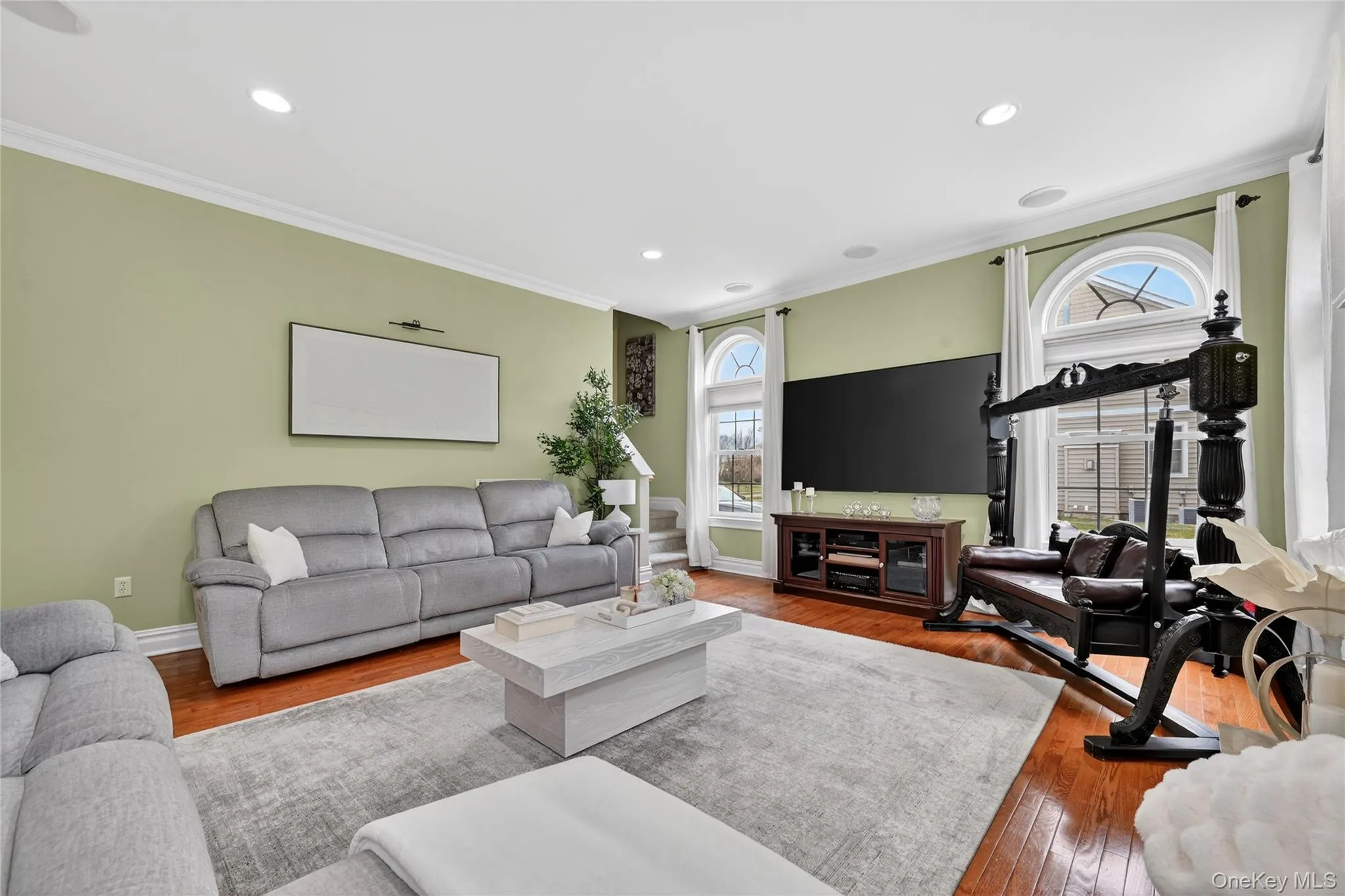 Living room featuring hardwood flooring, recessed lighting, crown molding, and arched windows Living room featuring hardwood flooring, recessed lighting, crown molding, and arched windows