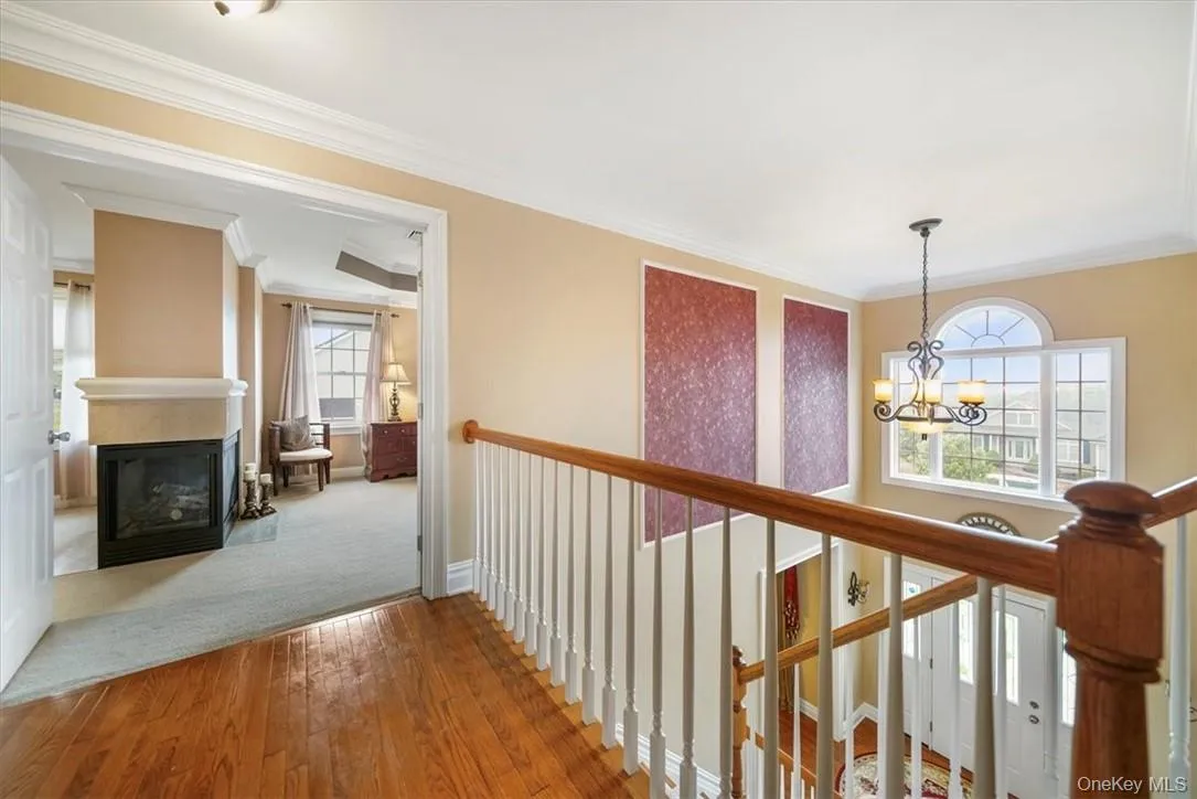 Hall featuring hardwood / wood-style floors, a chandelier, and crown molding Hall featuring hardwood / wood-style floors, a chandelier, and crown molding