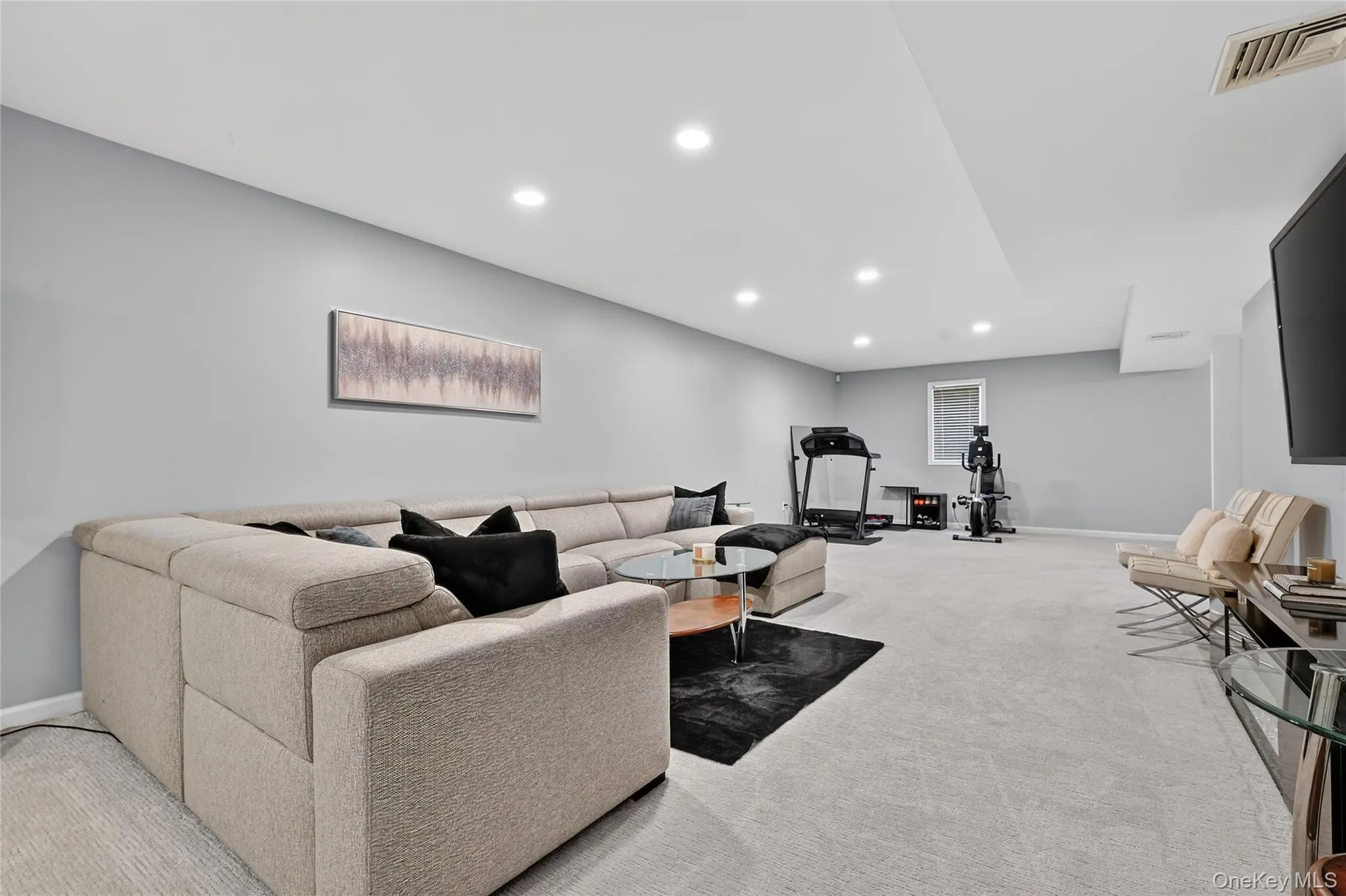 Spacious room featuring light gray walls, recessed lighting, and light-colored carpeting throughout Spacious room featuring light gray walls, recessed lighting, and light-colored carpeting throughout