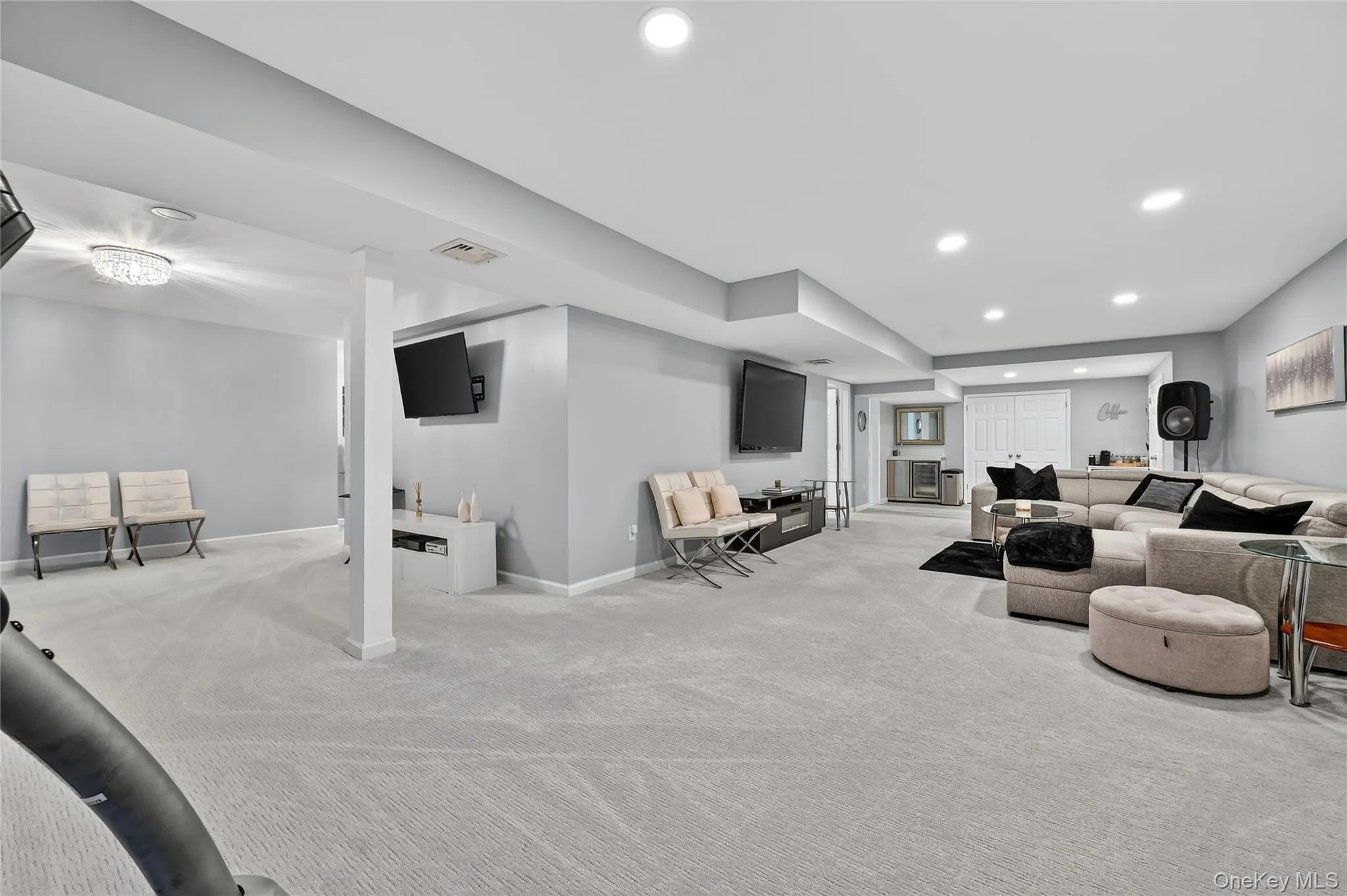 Expansive lower-level space featuring light gray walls, recessed lighting, and soft gray carpet flooring Expansive lower-level space featuring light gray walls, recessed lighting, and soft gray carpet flooring