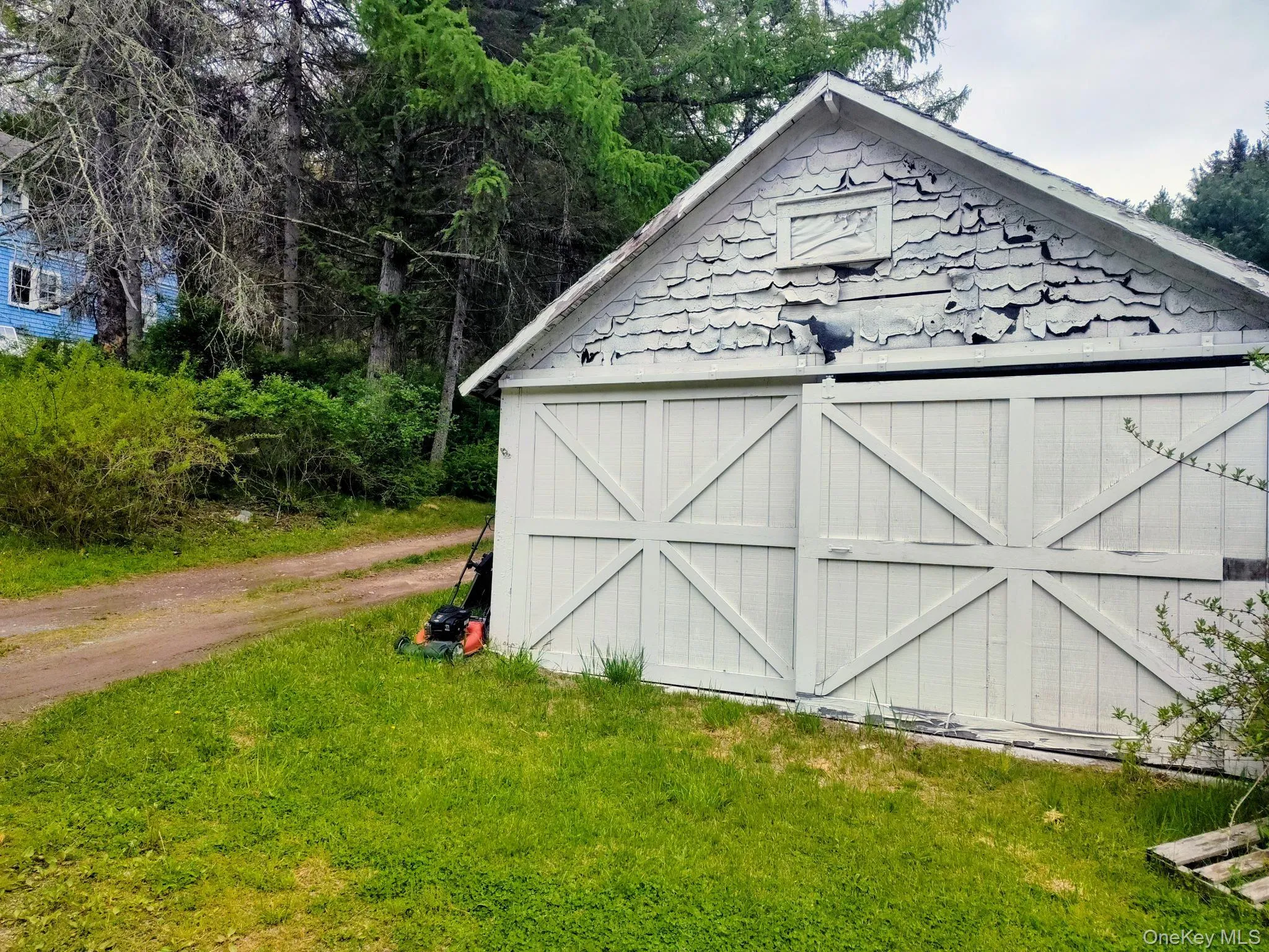 Detached storage building featuring horizontal wood siding, a gable roofline, and decorative shingle siding Detached storage building featuring horizontal wood siding, a gable roofline, and decorative shingle siding