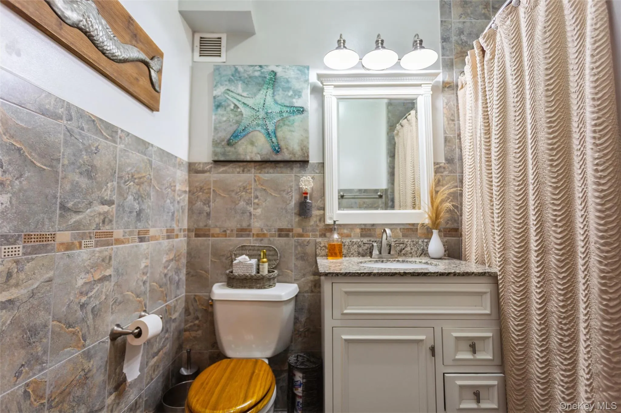 Beautifully renovated bathroom with custom tilework, granite vanity, and updated fixtures. Beautifully renovated bathroom with custom tilework, granite vanity, and updated fixtures.