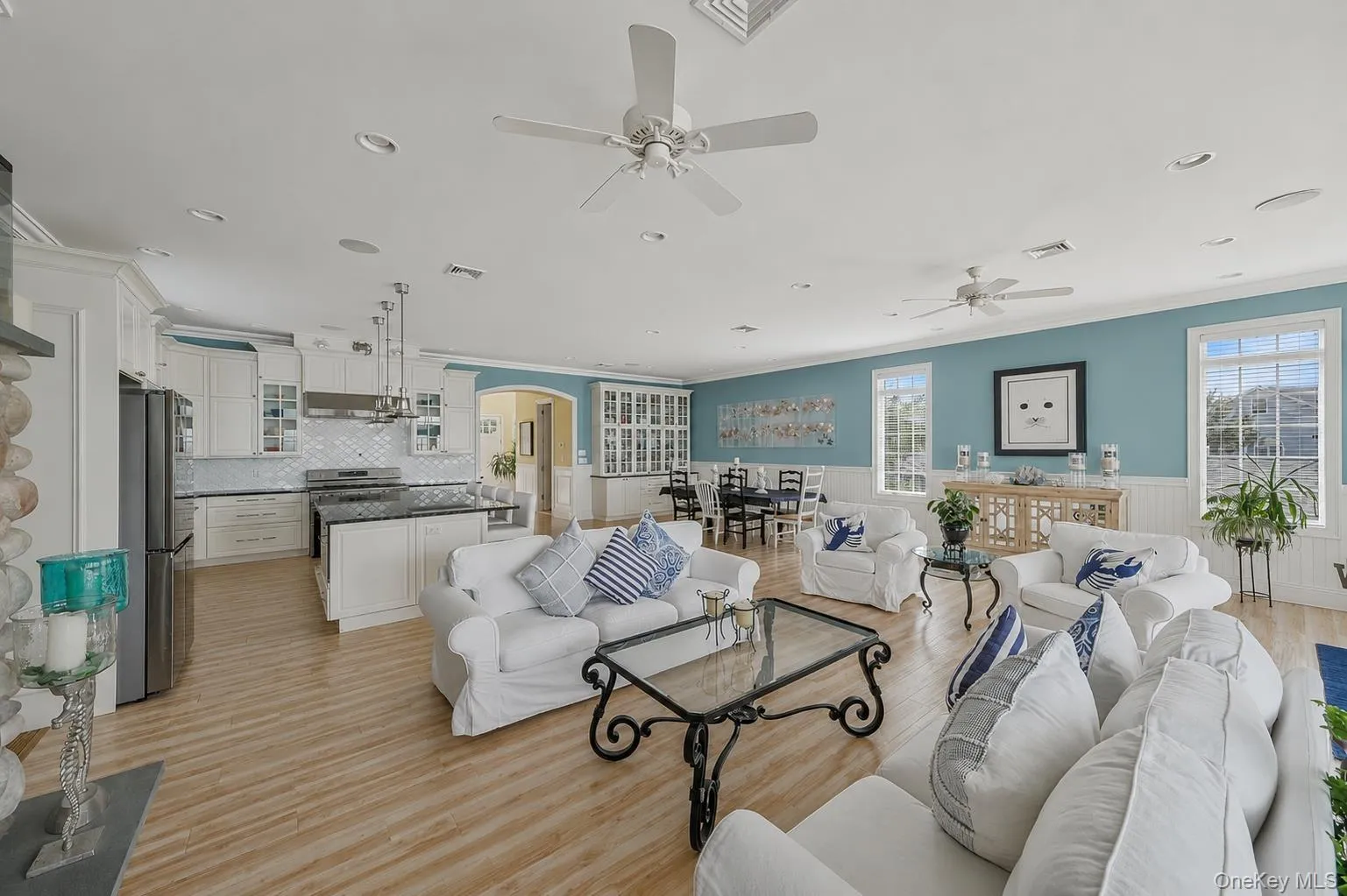 Open-concept living area featuring wood-finish flooring, recessed lighting, and multiple ceiling fans Open-concept living area featuring wood-finish flooring, recessed lighting, and multiple ceiling fans