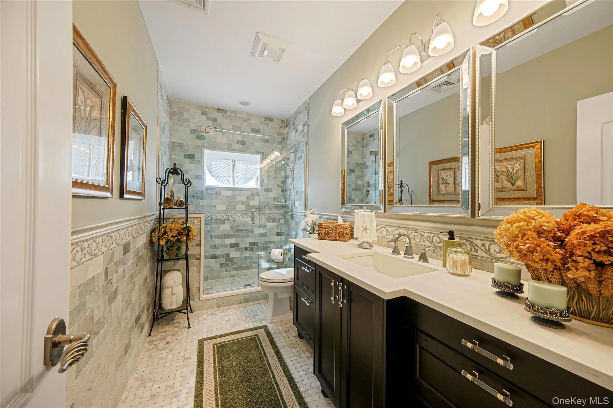 Bathroom featuring a double vanity with undermount sinks, a large walk-in shower with clear glass enclosure, and extensive tile work on walls and floor Bathroom featuring a double vanity with undermount sinks, a large walk-in shower with clear glass enclosure, and extensive tile work on walls and floor