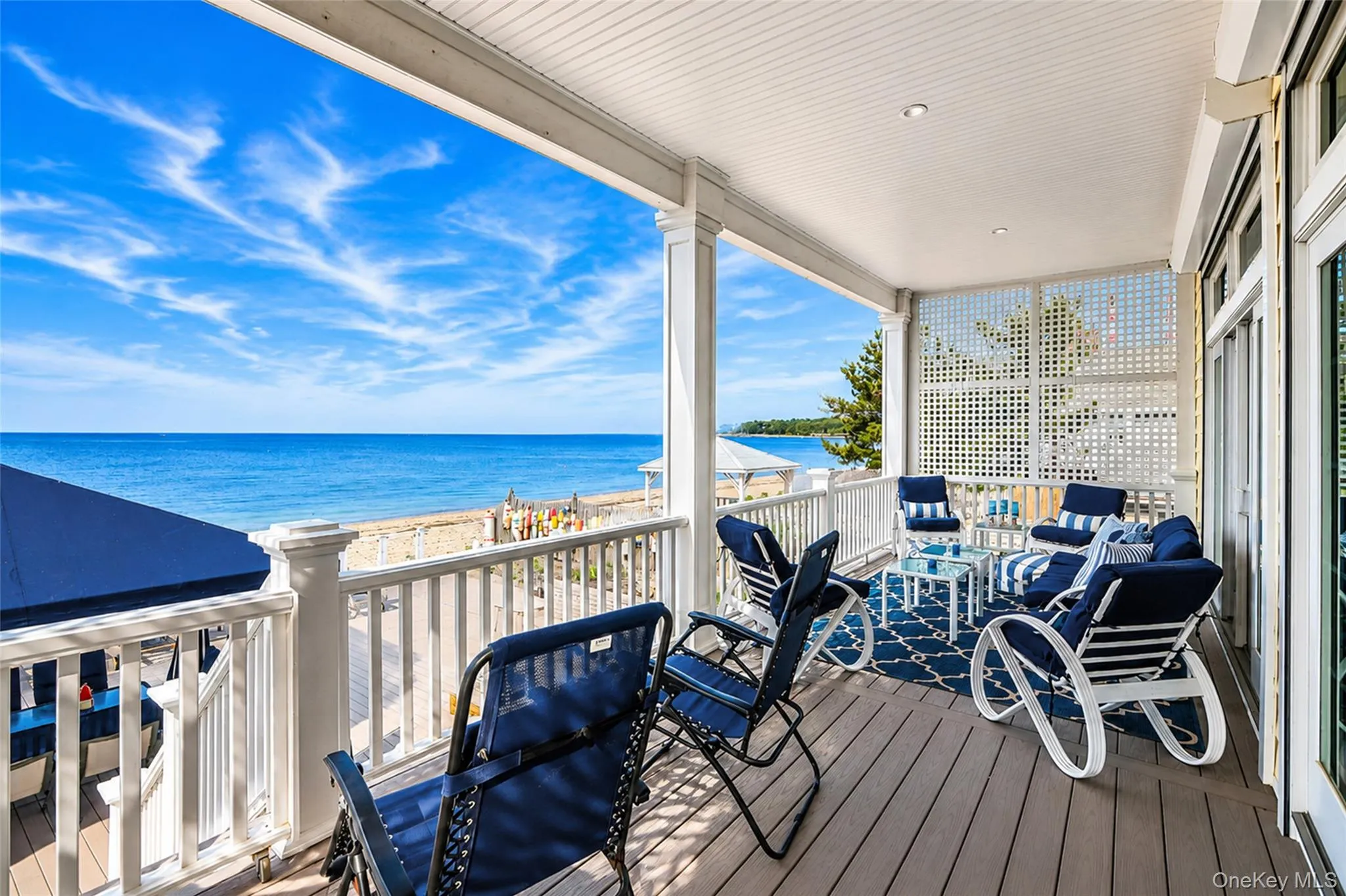 Expansive covered porch featuring procell decking, white railings, and a lattice privacy screen Expansive covered porch featuring procell decking, white railings, and a lattice privacy screen