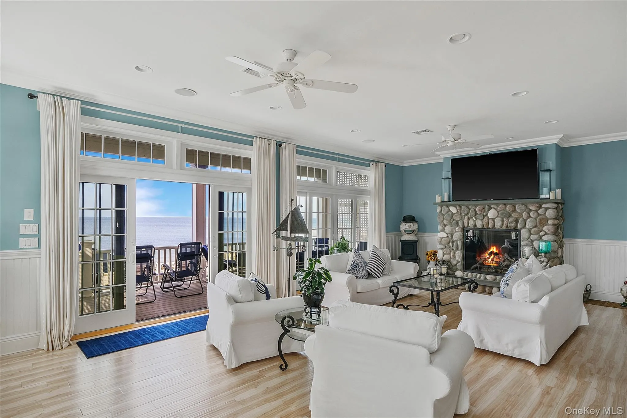 Spacious living area featuring light wood-finish flooring, a stone fireplace, and a large sliding glass door opening to a private balcony Spacious living area featuring light wood-finish flooring, a stone fireplace, and a large sliding glass door opening to a private balcony