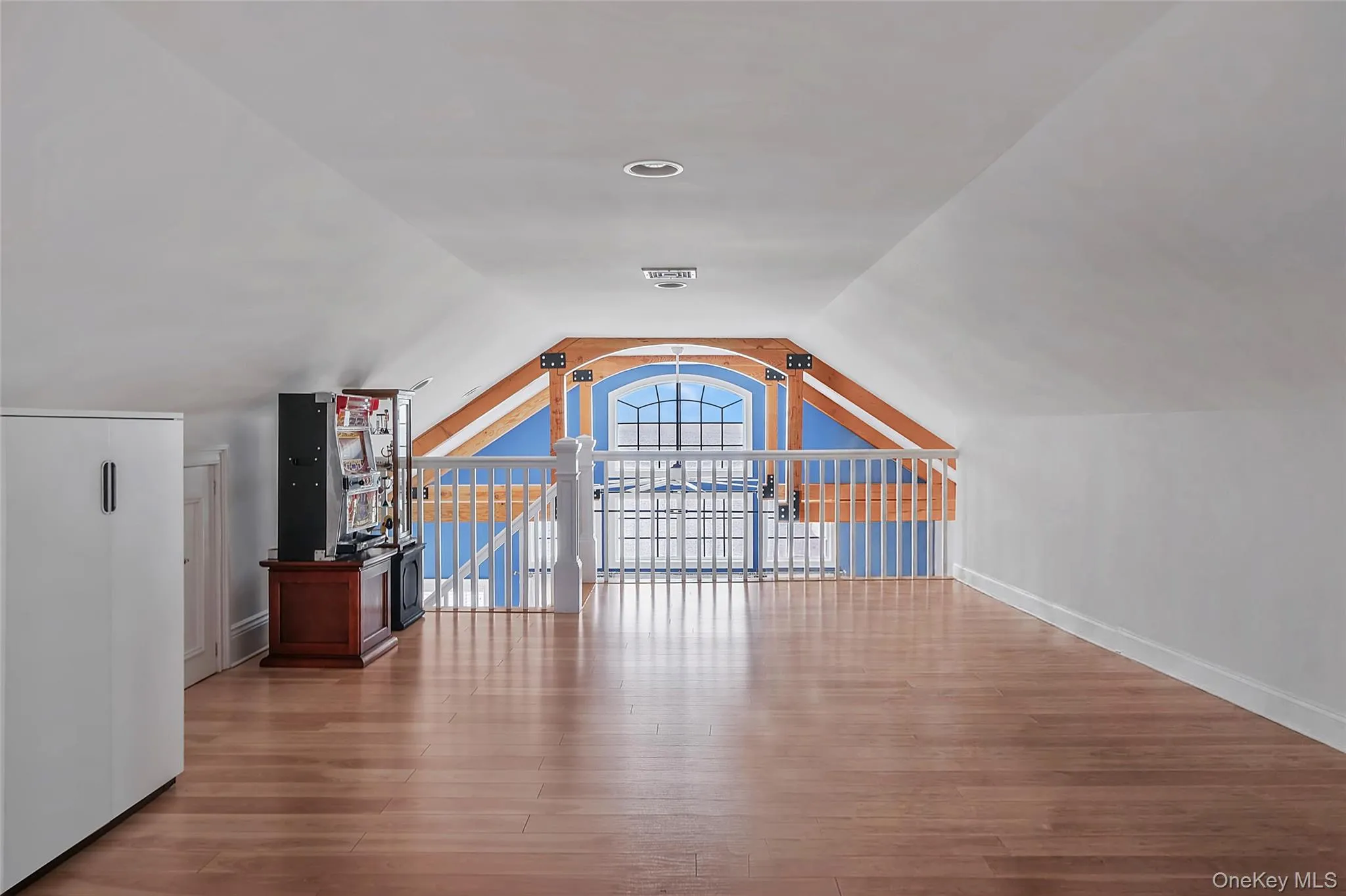 Spacious loft room featuring wood-finish flooring, sloped ceilings, and recessed lighting Spacious loft room featuring wood-finish flooring, sloped ceilings, and recessed lighting
