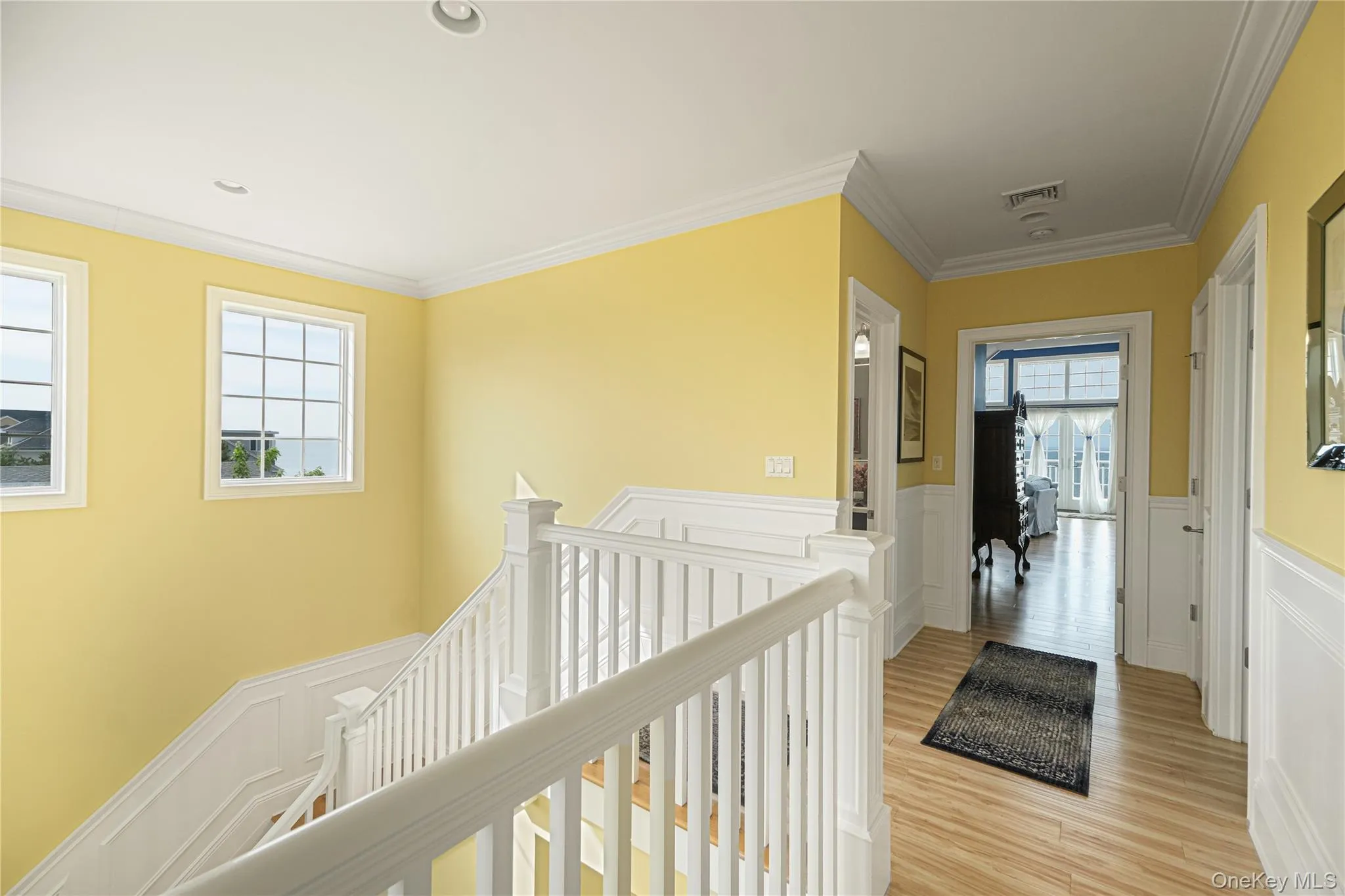 Staircase featuring white balusters and wood-finish treads, complemented by wainscoting and crown molding Staircase featuring white balusters and wood-finish treads, complemented by wainscoting and crown molding