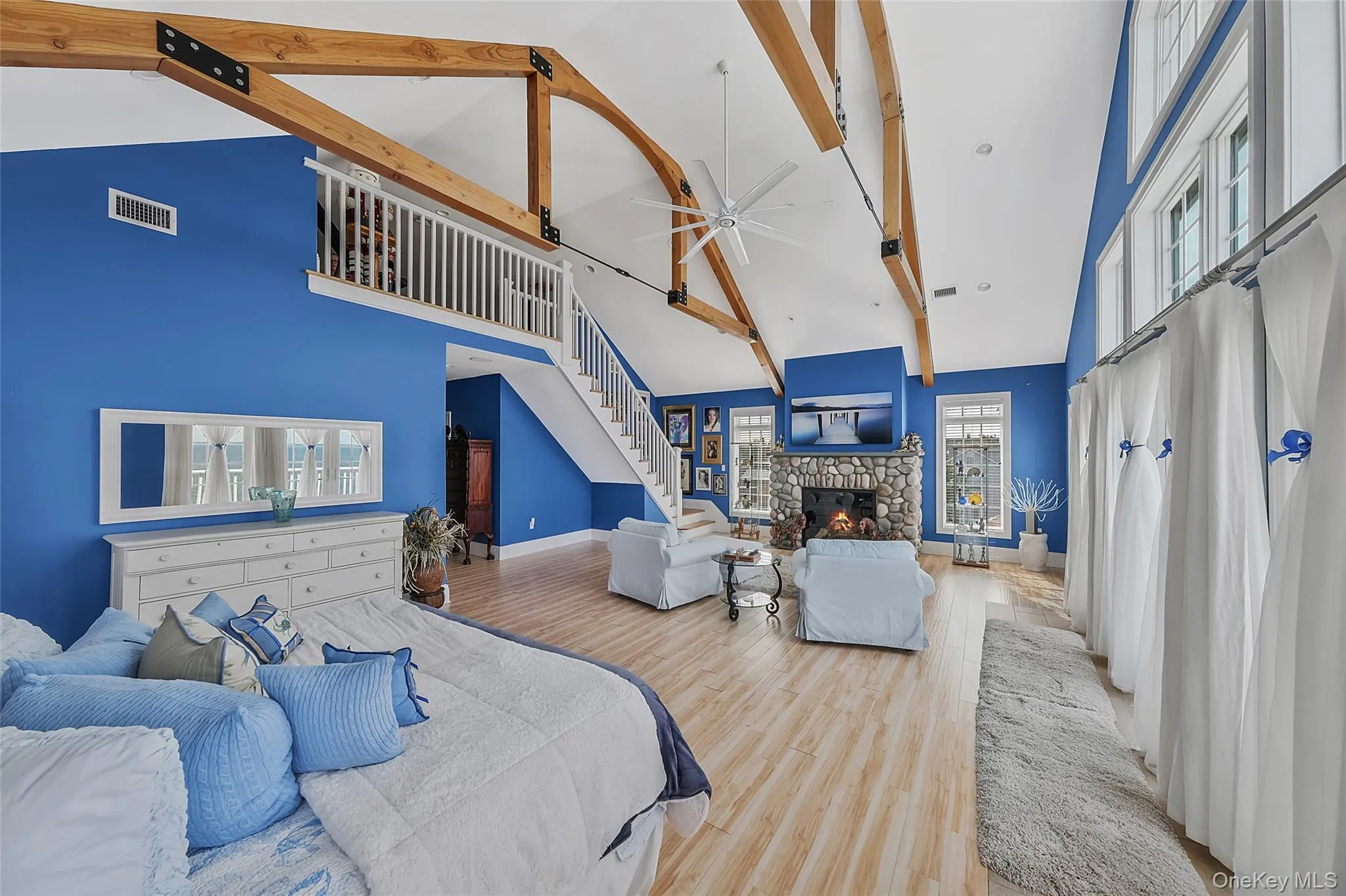 Vaulted ceilings with exposed wood beams, a stone-clad gas fireplace, and multiple window panels create a bright interior Vaulted ceilings with exposed wood beams, a stone-clad gas fireplace, and multiple window panels create a bright interior