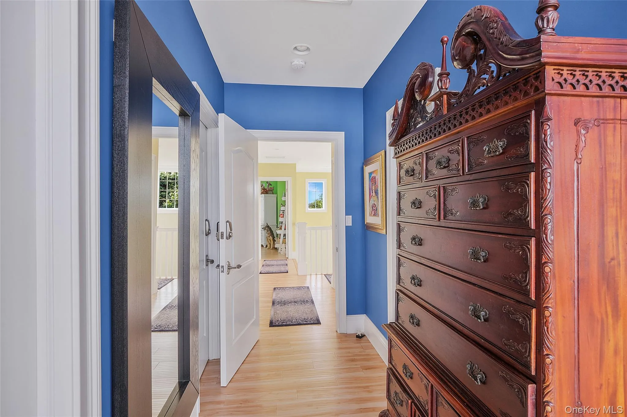 Hallway featuring wood-finish flooring, recessed lighting, and white baseboards Hallway featuring wood-finish flooring, recessed lighting, and white baseboards