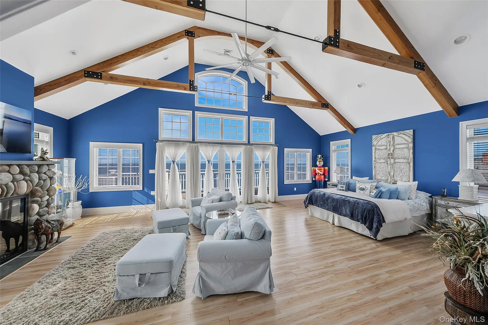 Vaulted ceilings with exposed wood beams, a stone-clad gas fireplace, and multiple window panels create a bright interior, views of the long island sound and on clear day you can see CT Vaulted ceilings with exposed wood beams, a stone-clad gas fireplace, and multiple window panels create a bright interior, views of the long island sound and on clear day you can see CT
