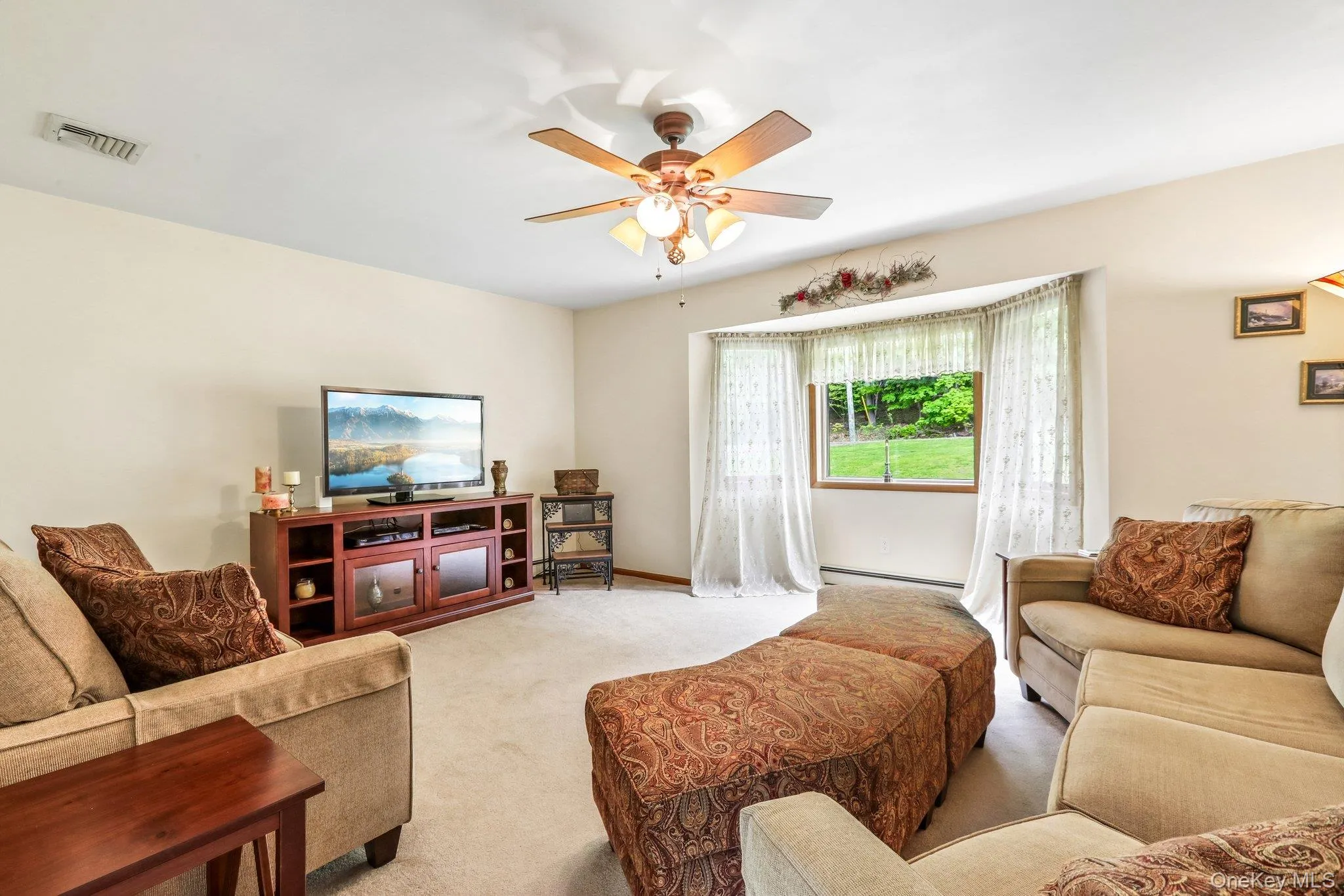 Living room with lots of natural light and a ceiling fan. There is hardwood under the carpet. Living room with lots of natural light and a ceiling fan. There is hardwood under the carpet.