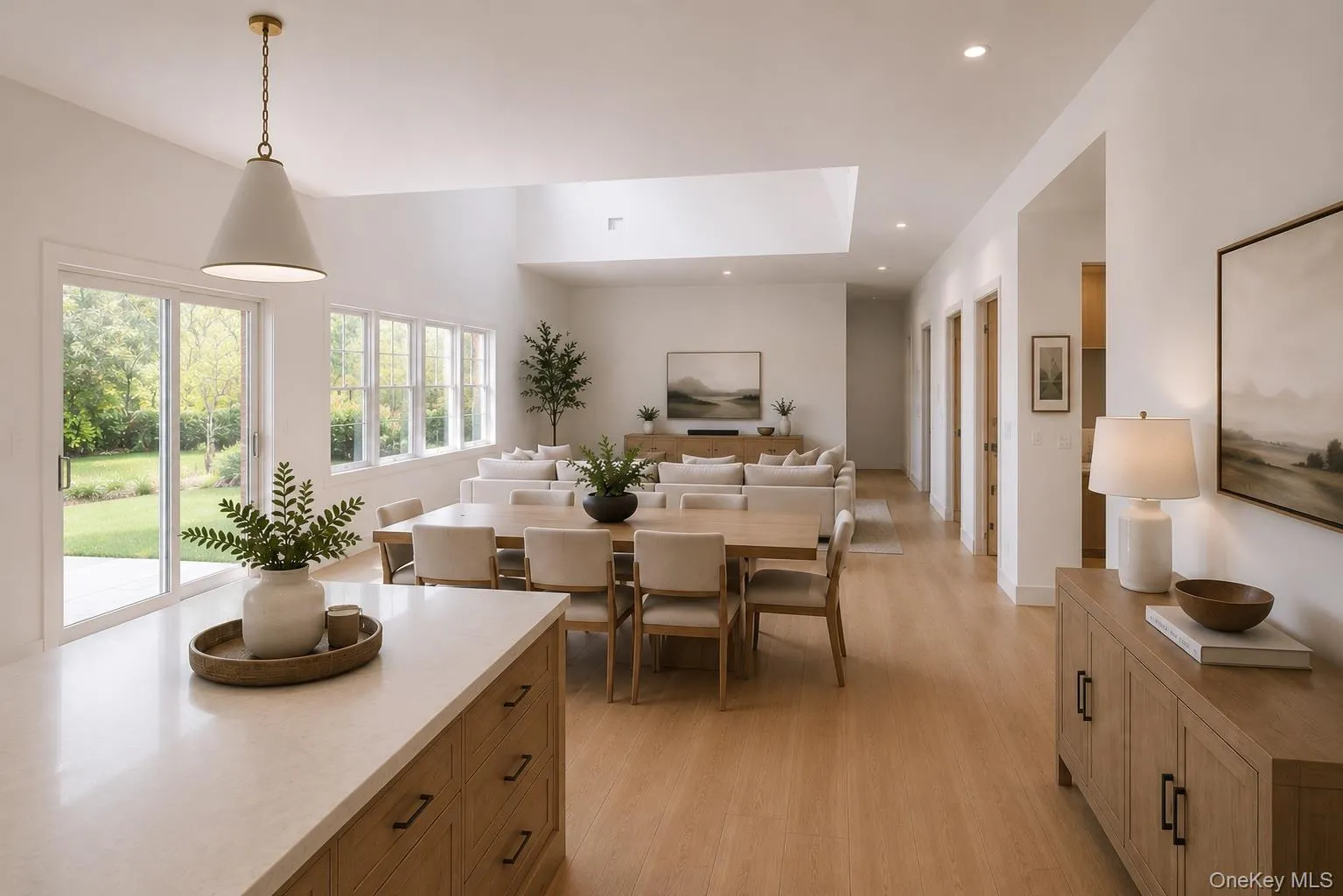 Bright, open-concept living space featuring wood-finish flooring, a vaulted ceiling with skylight, and extensive windows Bright, open-concept living space featuring wood-finish flooring, a vaulted ceiling with skylight, and extensive windows
