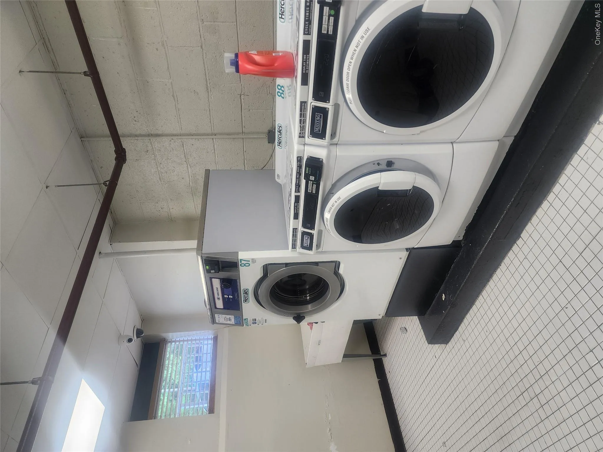 Laundry room featuring multiple front-load washing machines, a utility sink, and white square tile flooring Laundry room featuring multiple front-load washing machines, a utility sink, and white square tile flooring