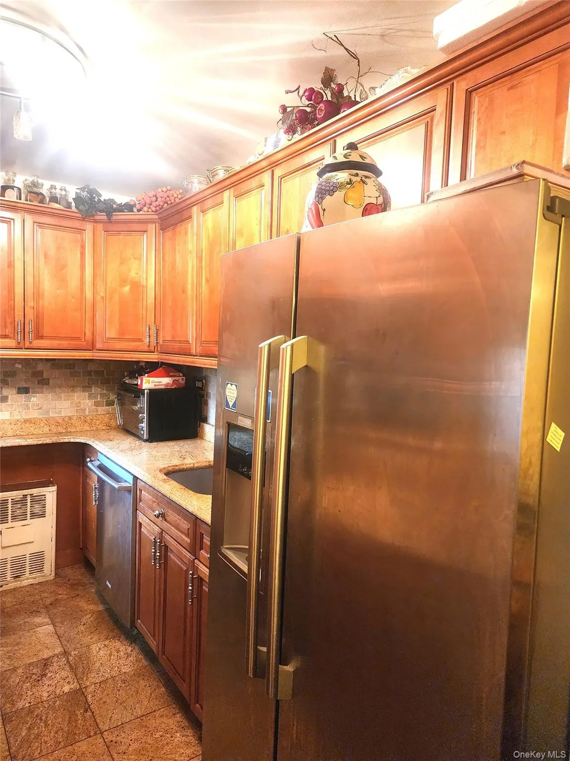 Kitchen featuring a large stainless steel refrigerator with integrated dispenser, wood cabinetry, granite countertops, and a tiled backsplash Kitchen featuring a large stainless steel refrigerator with integrated dispenser, wood cabinetry, granite countertops, and a tiled backsplash