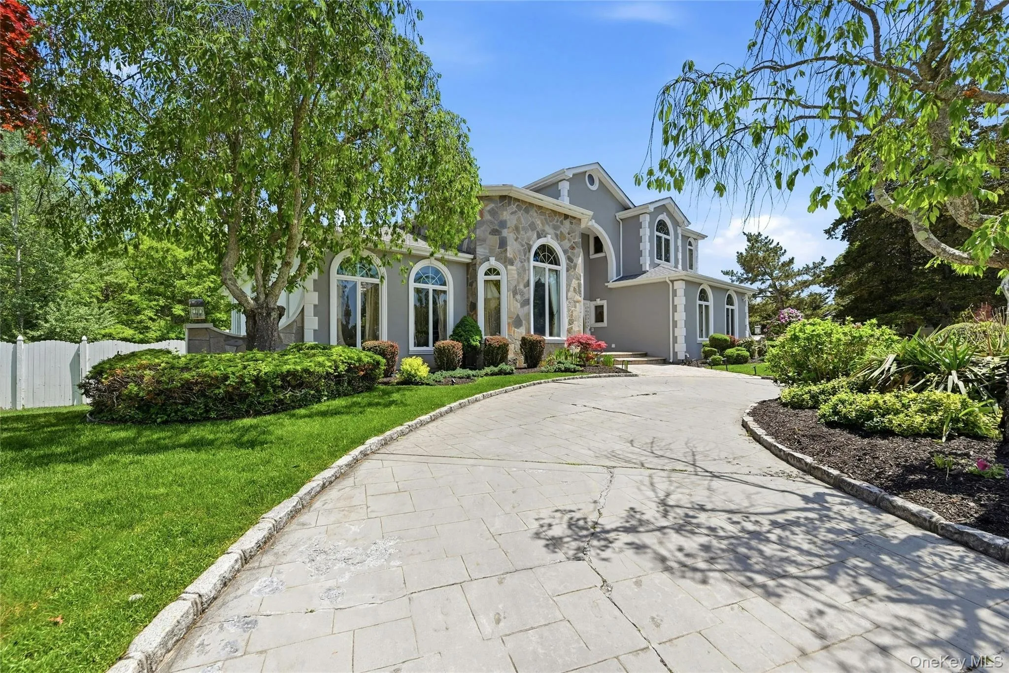 Stately exterior featuring a stone and stucco facade, arched windows, and a paved circular driveway Stately exterior featuring a stone and stucco facade, arched windows, and a paved circular driveway
