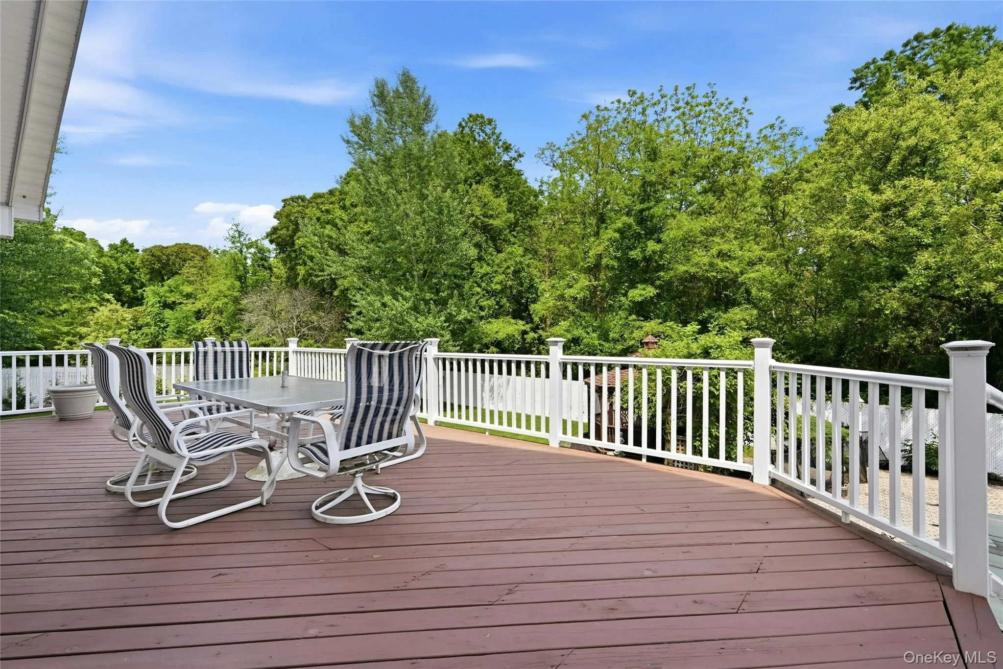 Spacious outdoor deck featuring rich wood-finish planks and white railings Spacious outdoor deck featuring rich wood-finish planks and white railings