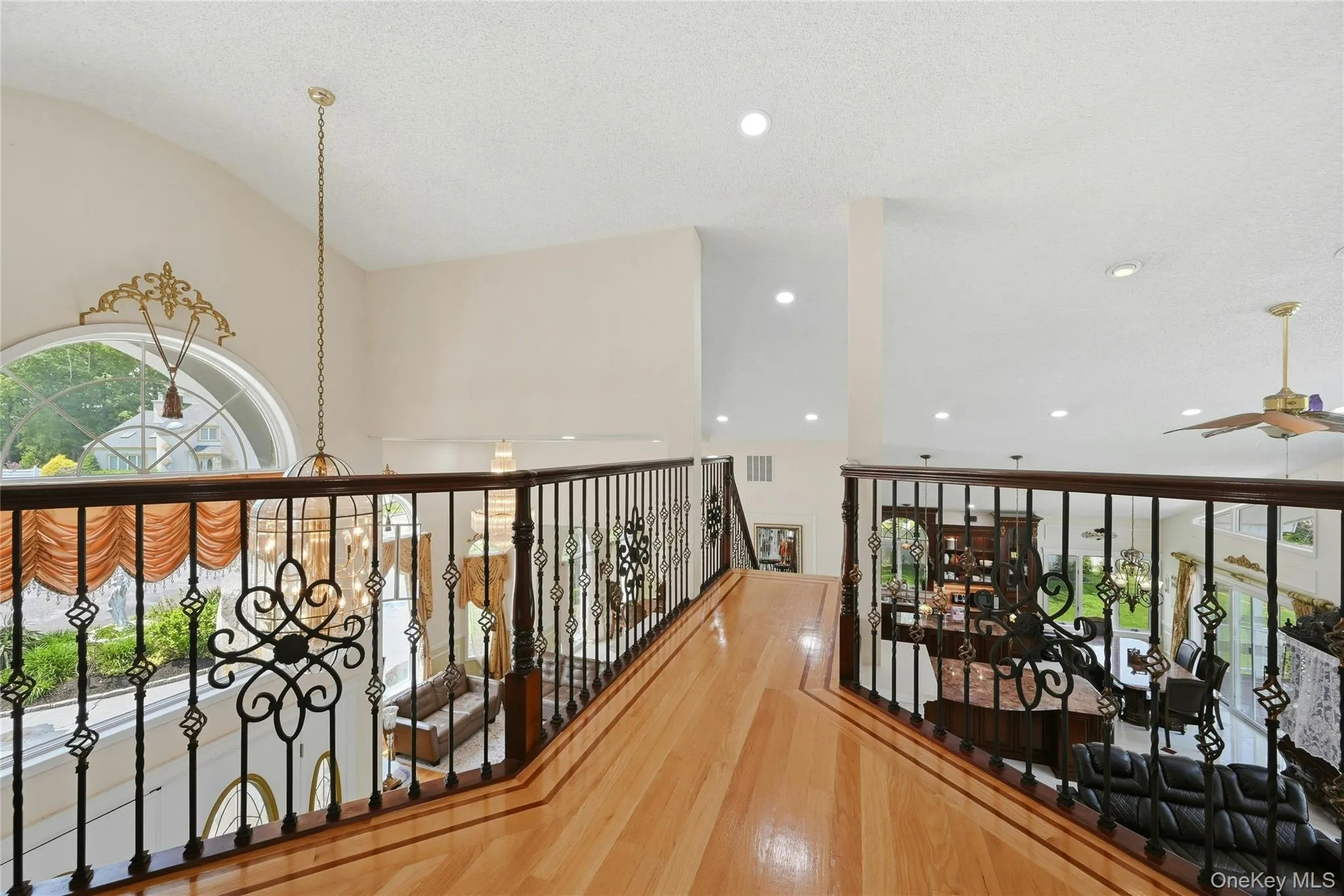 Second-story landing featuring decorative wrought iron balusters with wood-finish handrails and light wood-finish flooring Second-story landing featuring decorative wrought iron balusters with wood-finish handrails and light wood-finish flooring