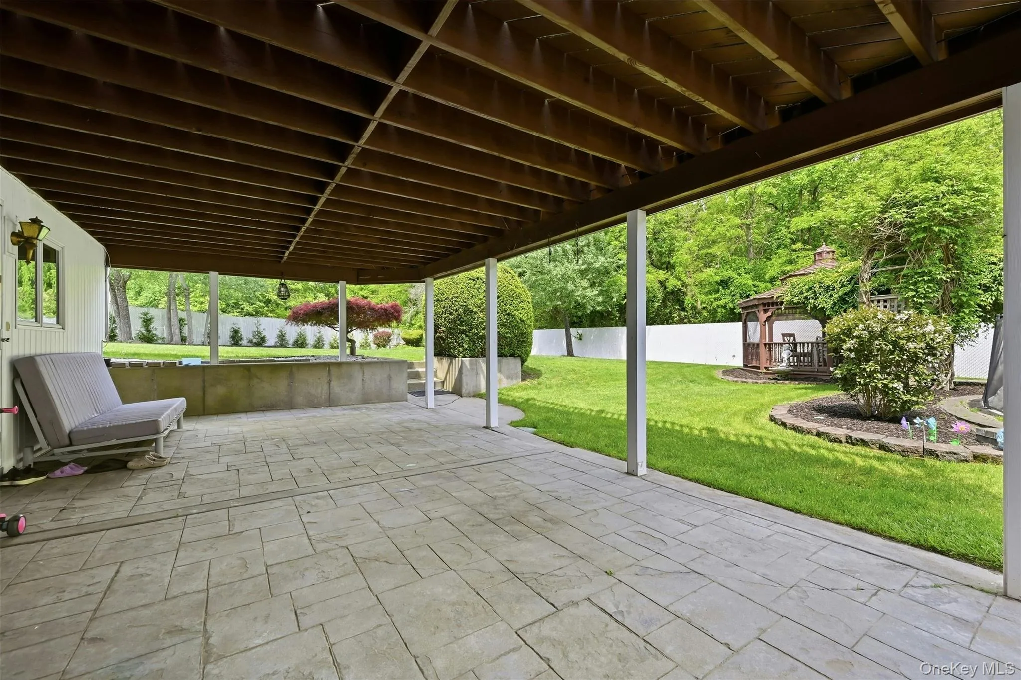 Expansive covered patio featuring stamped concrete flooring and structural support columns Expansive covered patio featuring stamped concrete flooring and structural support columns