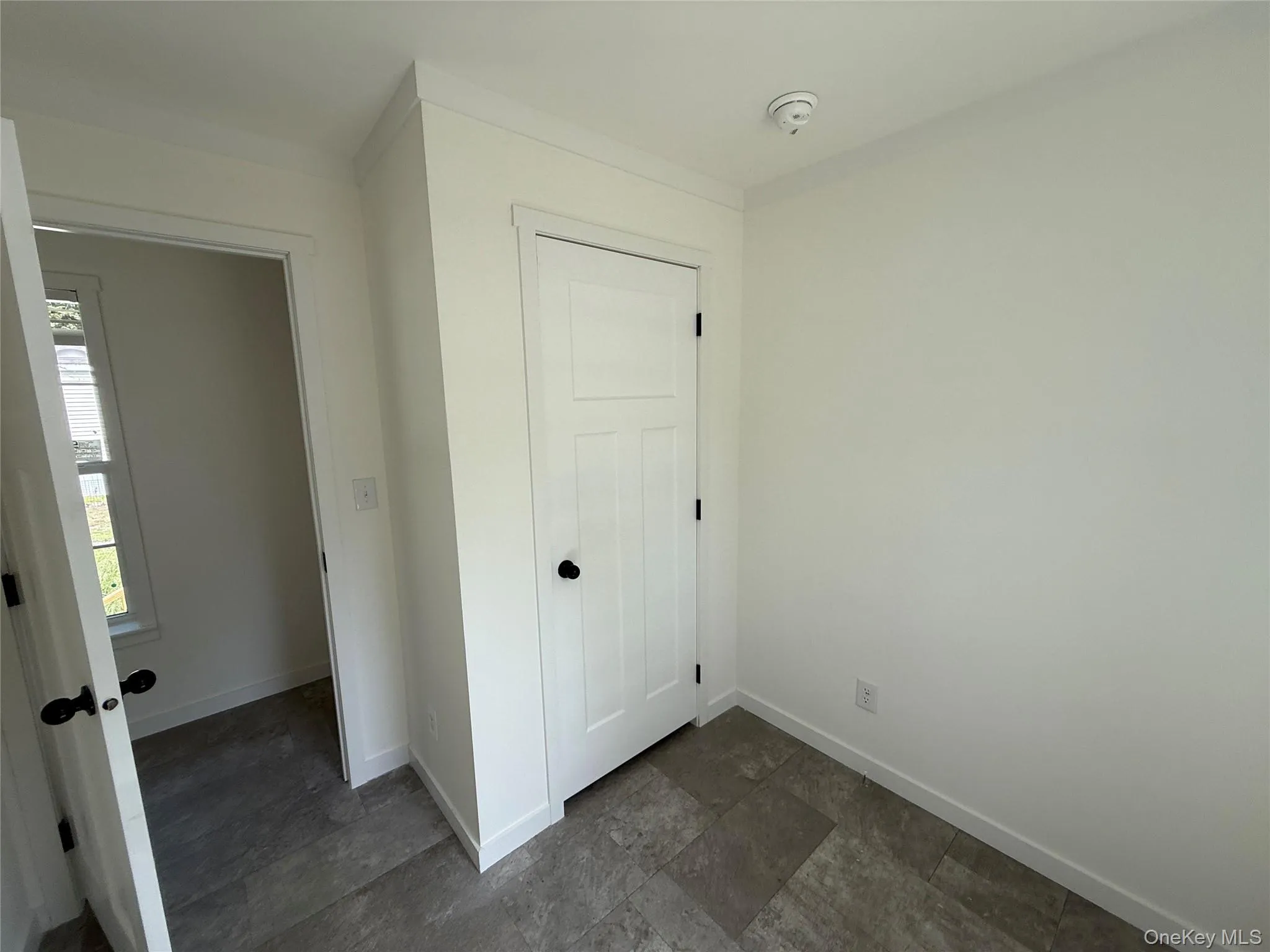 Unfurnished bedroom with a closet and dark stone finish floors Unfurnished bedroom with a closet and dark stone finish floors