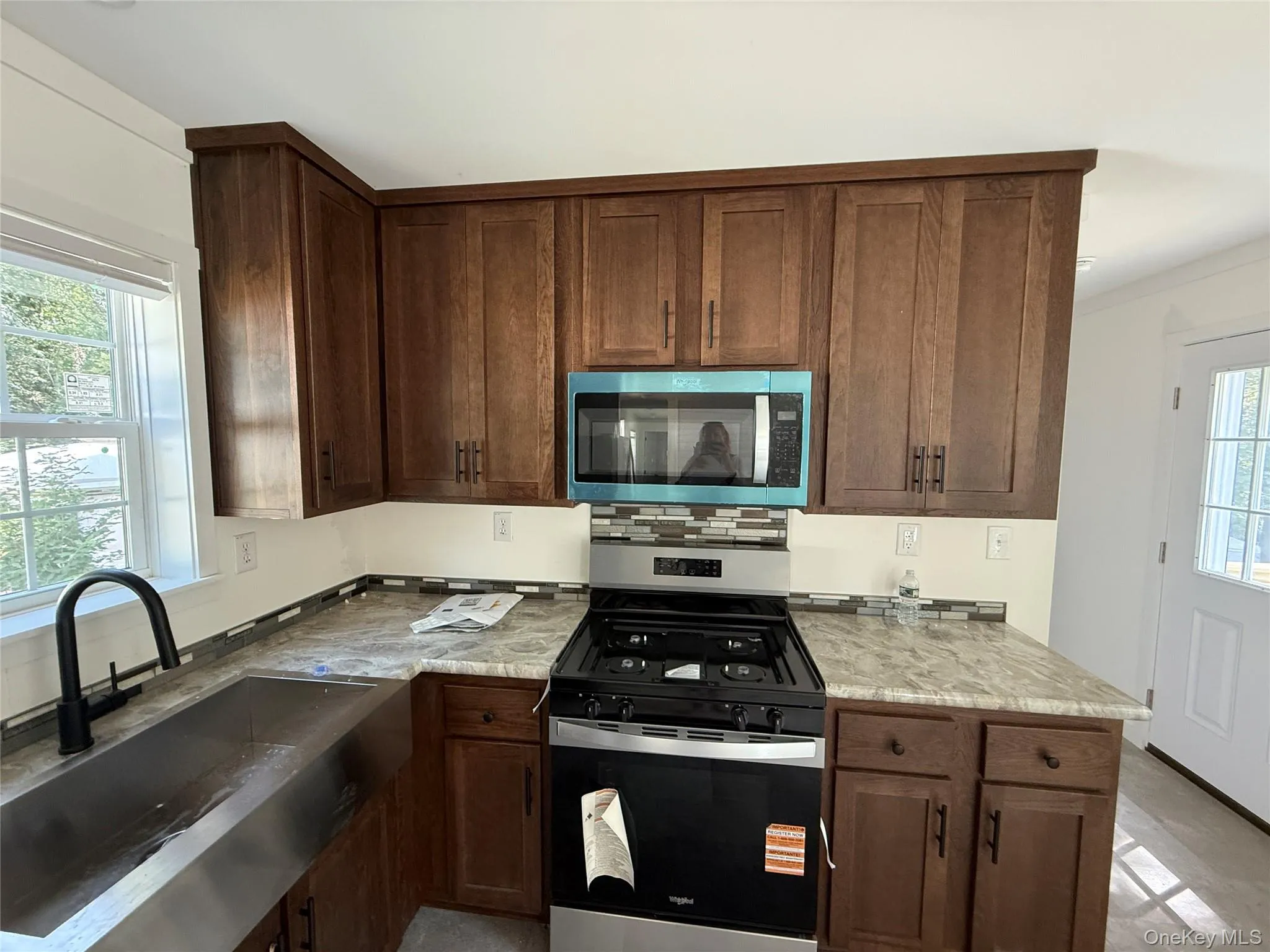 Kitchen featuring stainless steel appliances, tasteful backsplash, light countertops, ornamental molding, and dark brown cabinetry Kitchen featuring stainless steel appliances, tasteful backsplash, light countertops, ornamental molding, and dark brown cabinetry