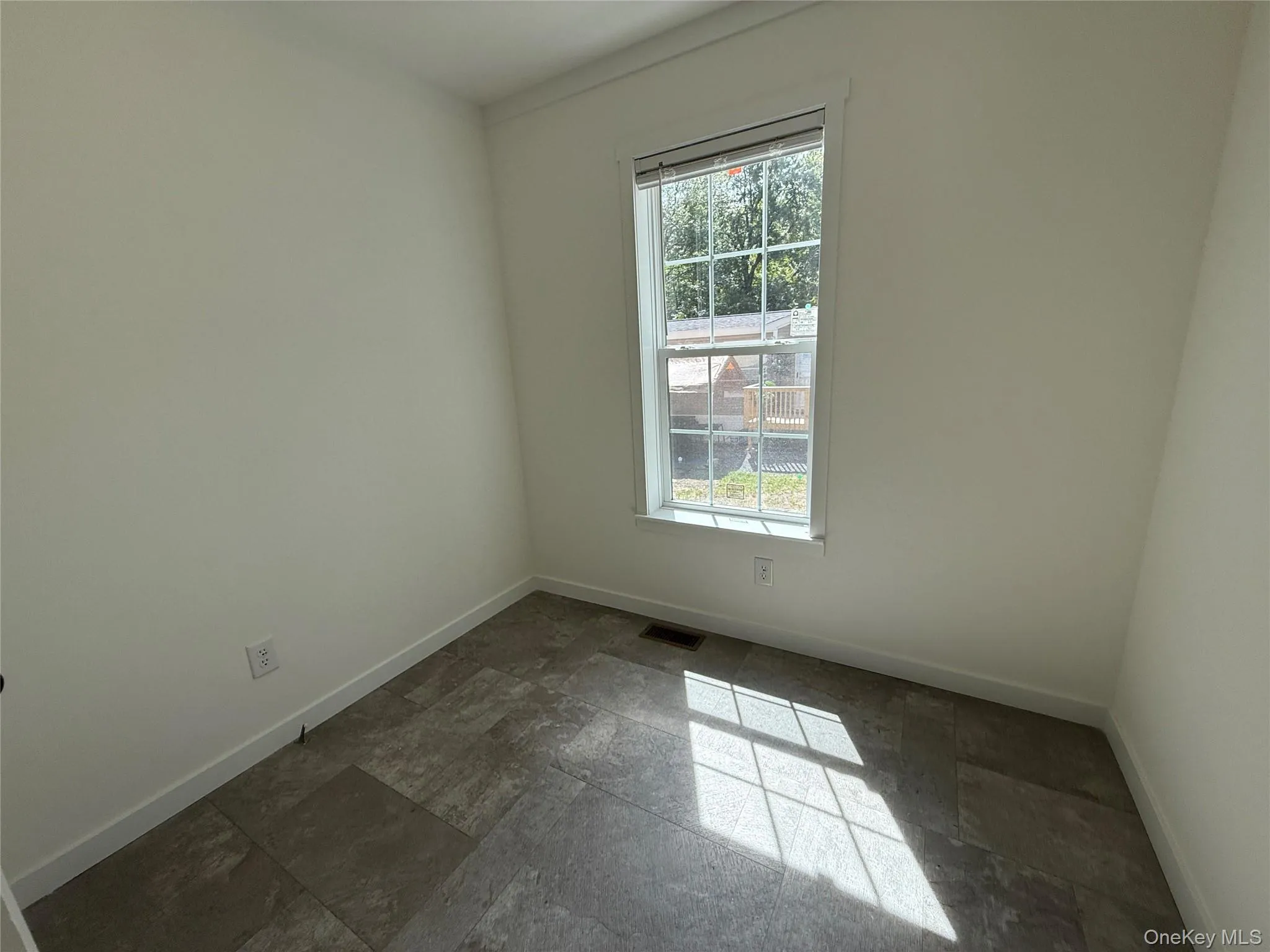 Spare room with stone tile flooring and baseboards Spare room with stone tile flooring and baseboards