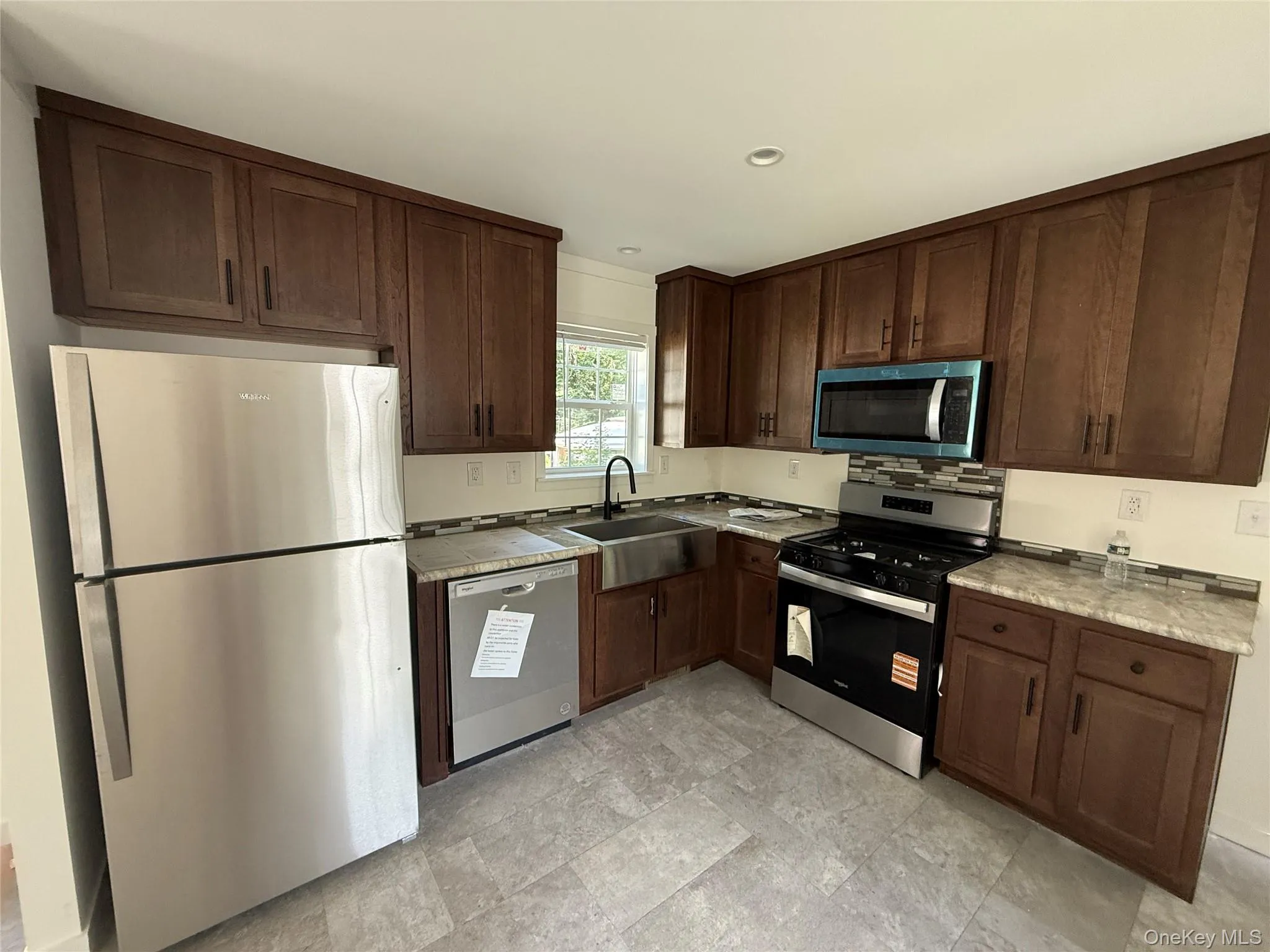 Kitchen with stainless steel appliances, dark brown cabinets, light countertops, and recessed lighting Kitchen with stainless steel appliances, dark brown cabinets, light countertops, and recessed lighting