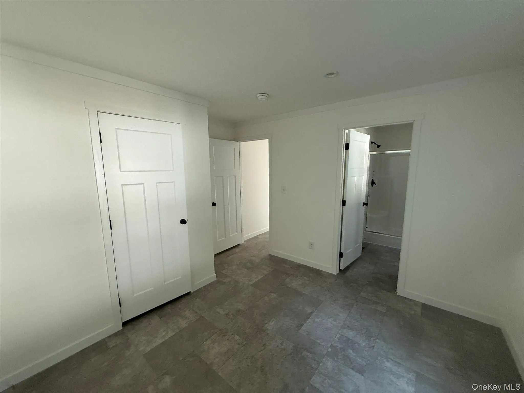 Unfurnished bedroom with ensuite bathroom and dark stone finish flooring Unfurnished bedroom with ensuite bathroom and dark stone finish flooring